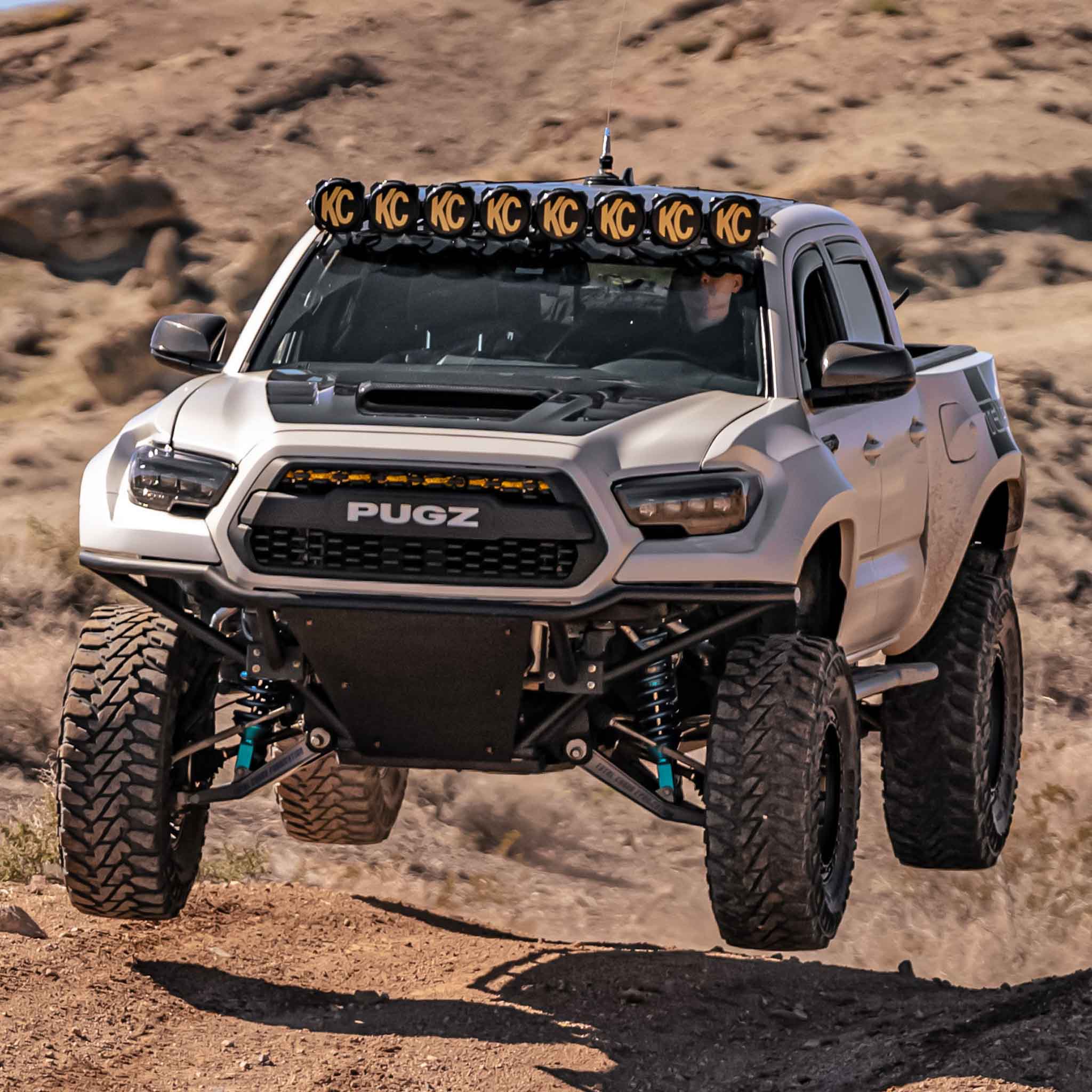 2016-2023 Toyota Tacoma fenders on a modified truck driving off-road, showcasing rugged design and performance features.
