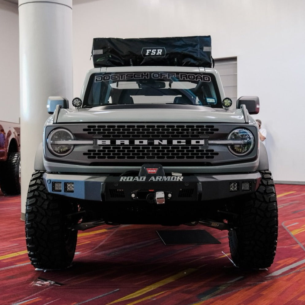 2021-2025 Ford Bronco with a heat extractor hood, showcasing rugged design and off-road capability in a showroom setting.