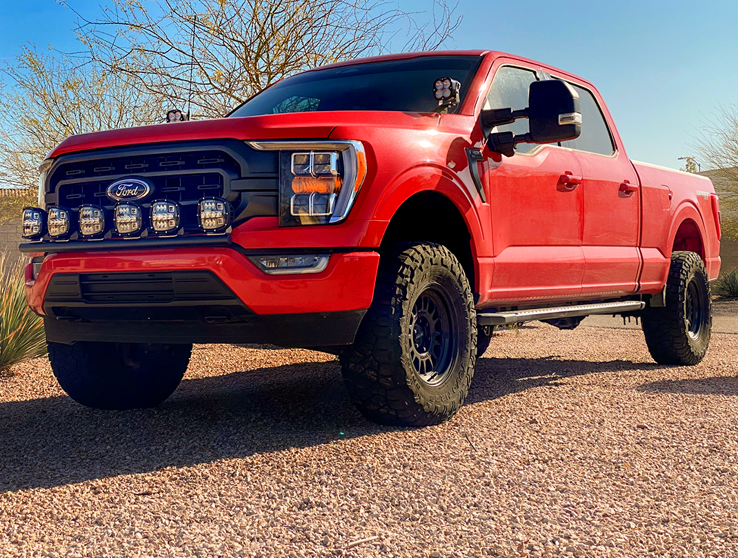 Front light mount for 2021-2023 Ford F150 on a red truck with off-road tires, showcasing enhanced lighting capability.