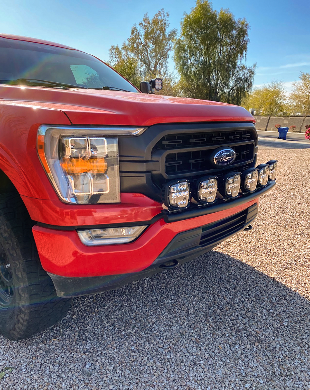Front light mount for 2021-2023 Ford F150, installed on stock bumper, featuring multiple auxiliary lights.