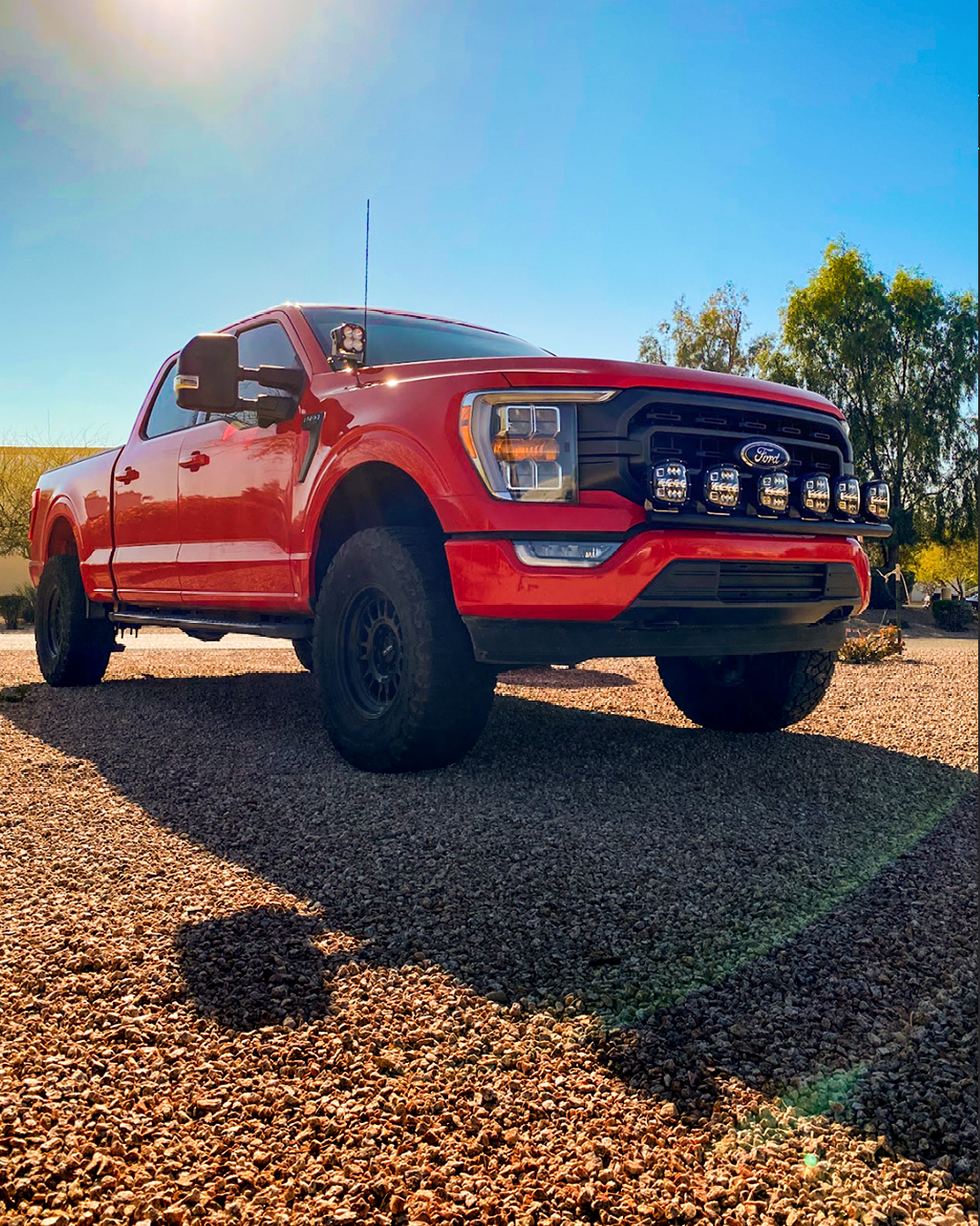 Front light mount for 2021-2023 Ford F150, showcasing a red truck with offroad lights on a gravel surface.