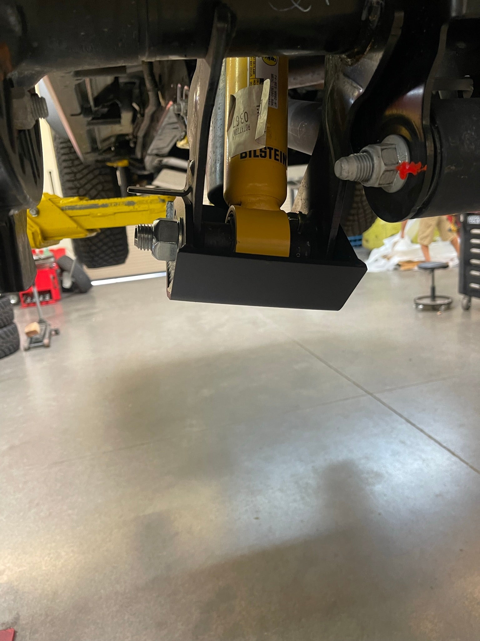 2021+ Bronco rear shock skid kit installed, featuring a black protective plate and yellow shock absorber.