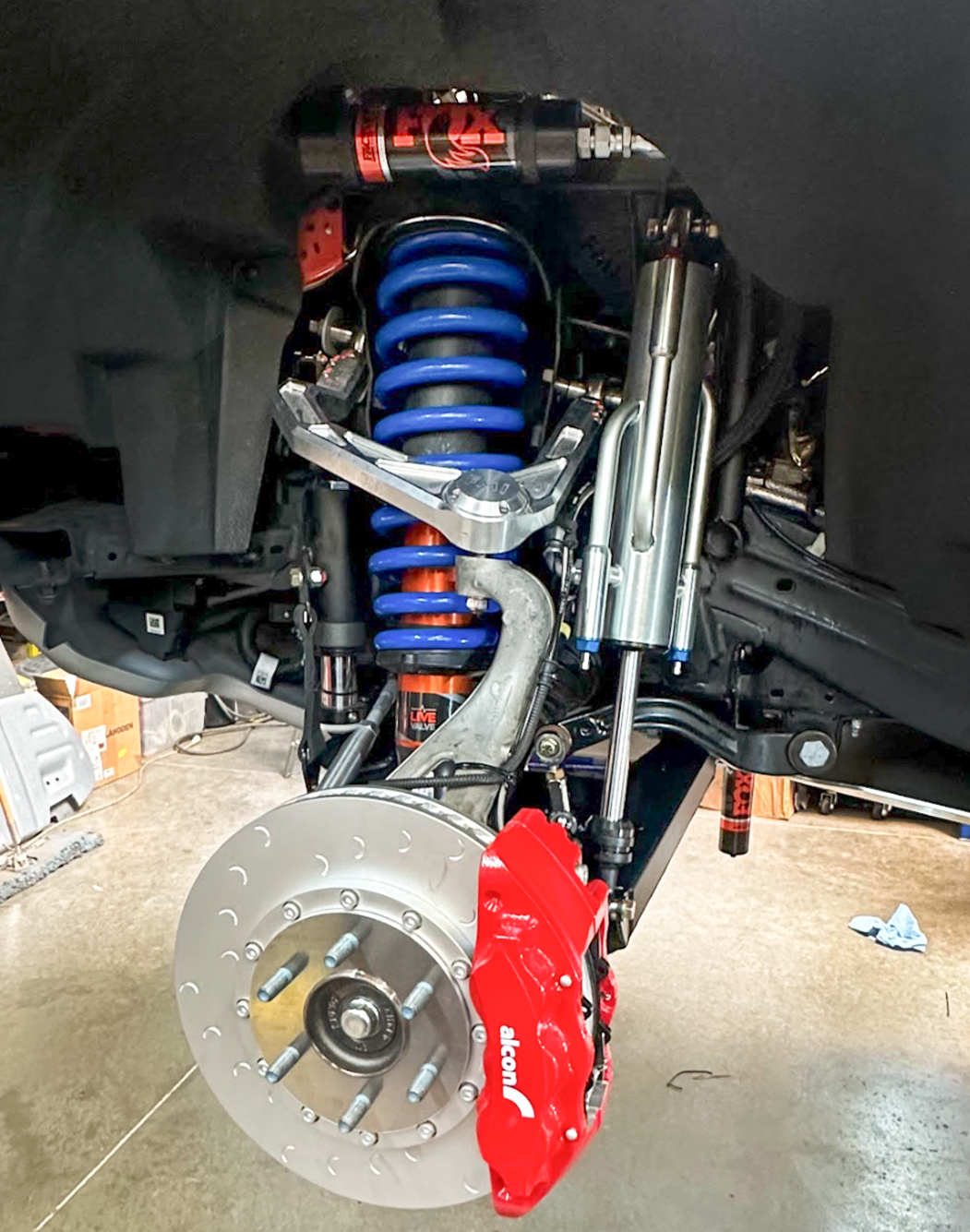 2022 Bronco Raptor mid travel front suspension kit showcasing blue coil springs, red brake caliper, and shock absorbers.
