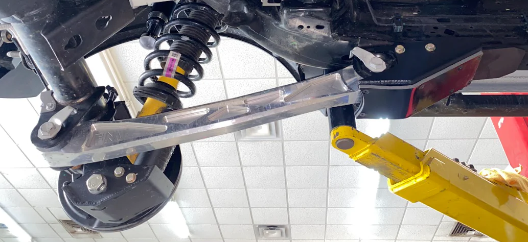2024 Ranger Raptor rear lower arm frame guard with HDPE slide installed, showcasing durable aluminum construction and suspension components.