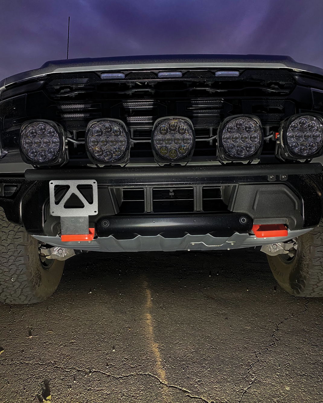 Front view of a 2024+ Gen 3.5 Raptor featuring a front tow hook license plate mount and off-road lights.