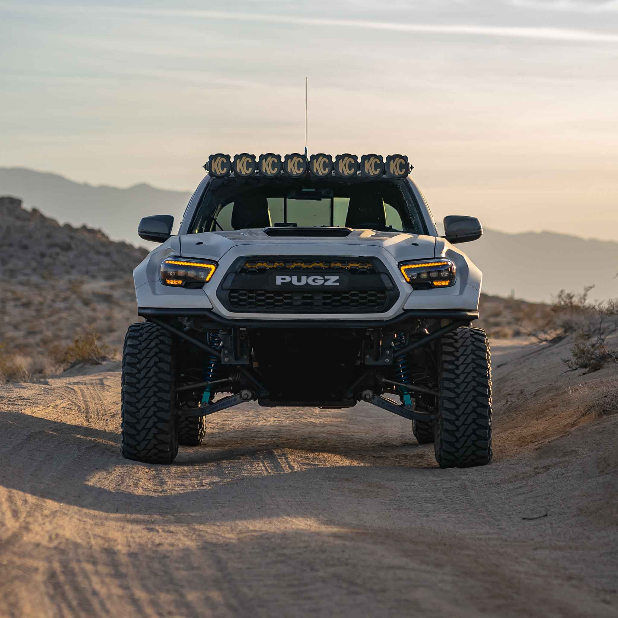 Front view of a modified 2016-2023 Toyota Tacoma with aftermarket fenders, showcasing offroad capabilities in a desert setting.