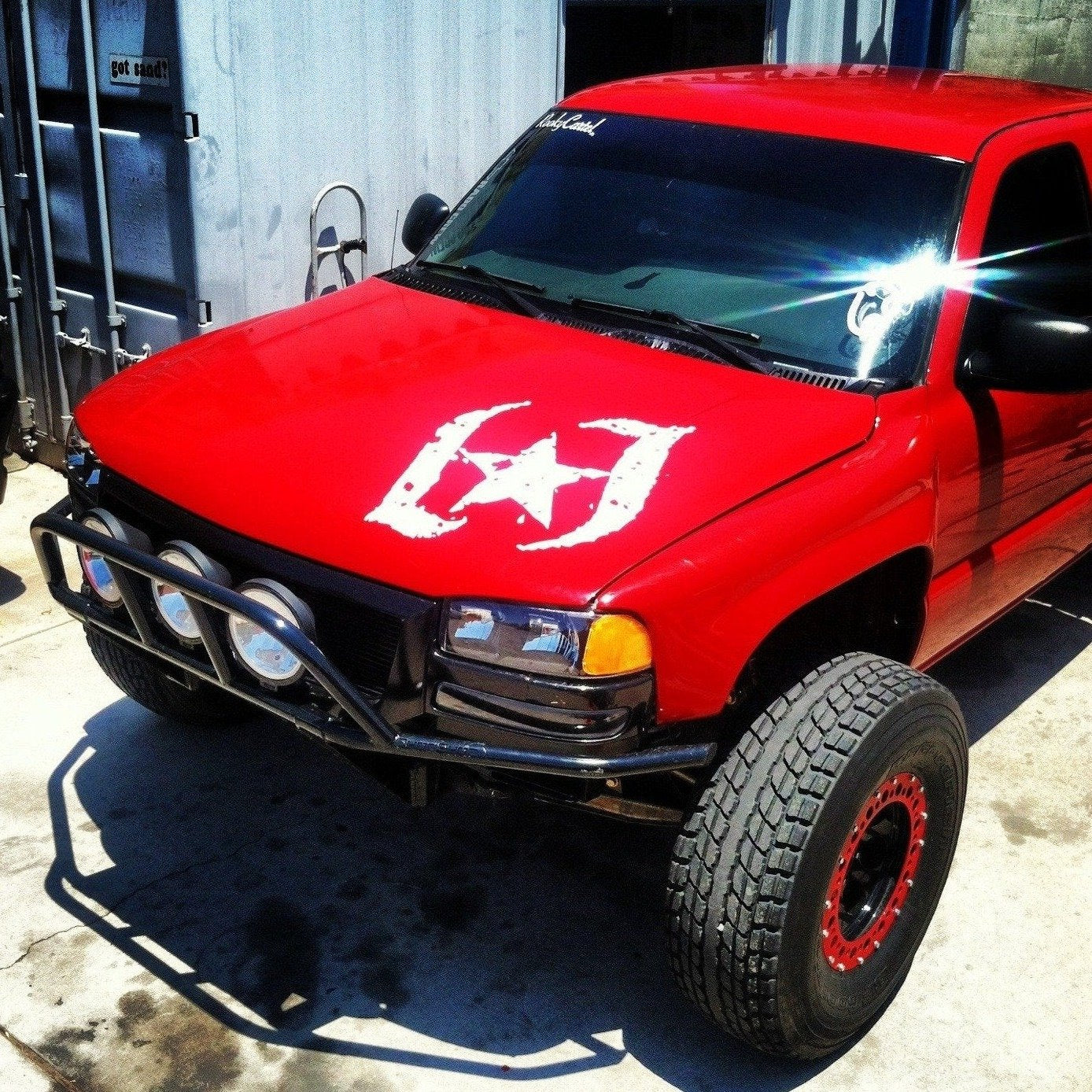 Red GMC Sierra with custom fenders and off-road modifications, showcasing rugged design and enhanced performance features.