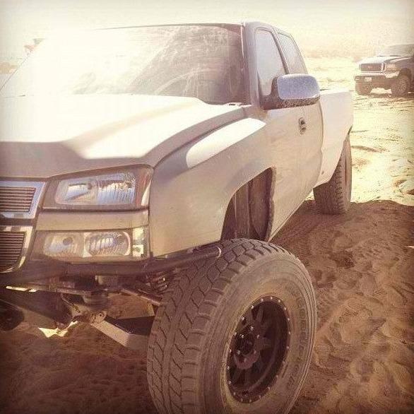 2003-2006 Chevrolet Silverado with aftermarket fenders, showcasing offroad capabilities in a sandy environment.