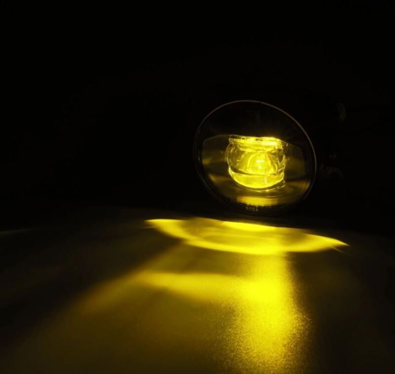 AlphaRex DoubleTap dual color LED fog light emitting a bright amber glow, designed for various vehicle models.