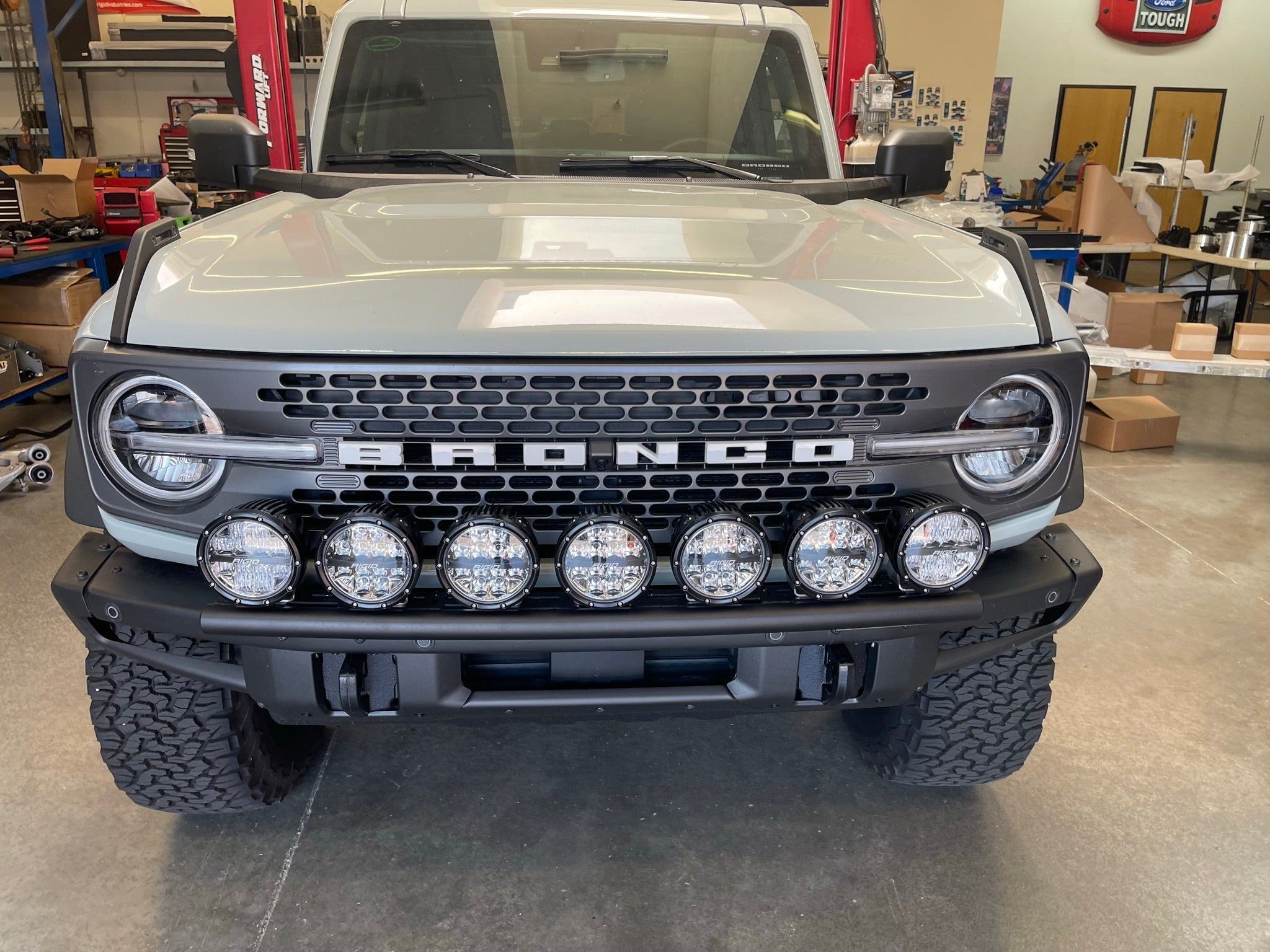 2022-UP Bronco Raptor front light mount kit showcasing multiple lights on a rugged vehicle in a workshop setting.