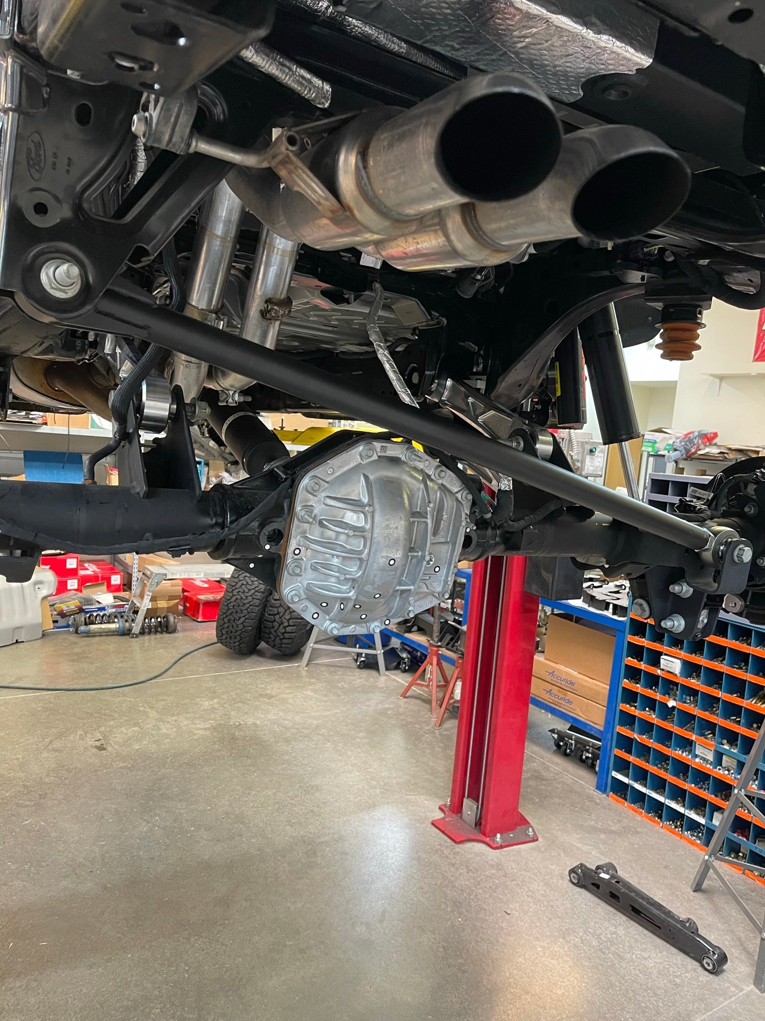 Bronco Raptor rear suspension kit featuring billet aluminum rear arms, showcasing undercarriage components and exhaust.