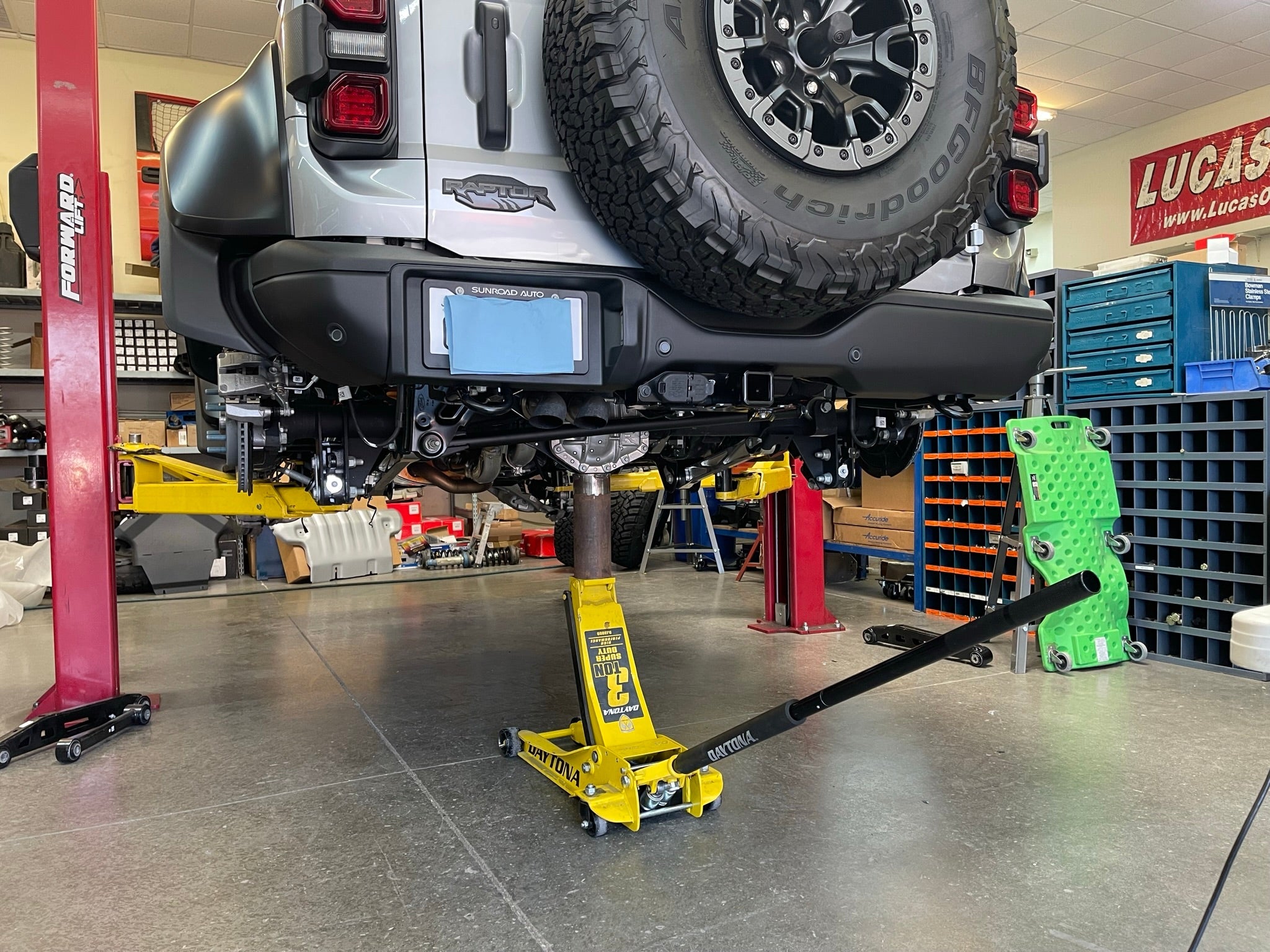 Bronco Raptor rear suspension kit featuring billet aluminum rear arms, installed on a lifted vehicle in a workshop.