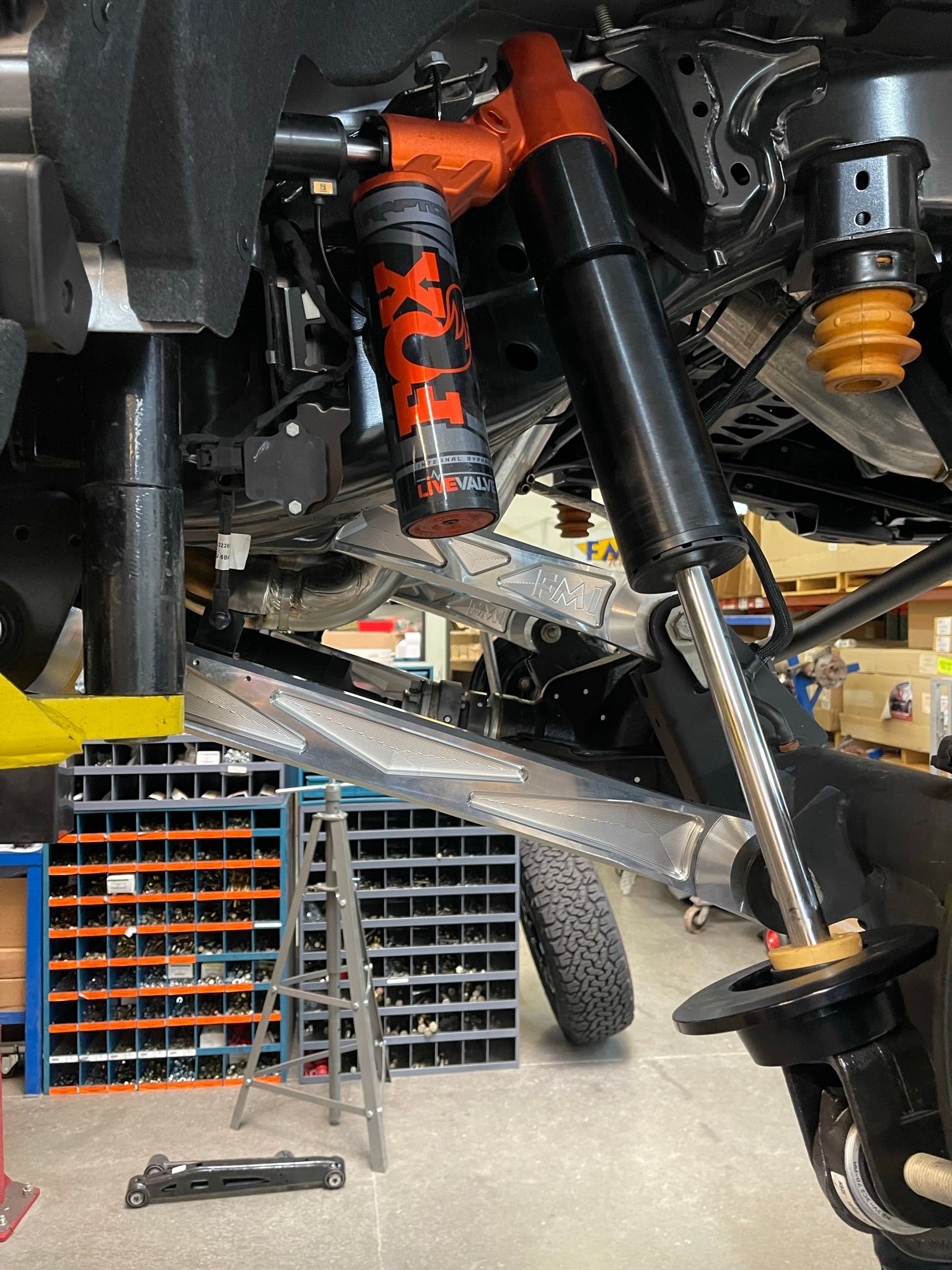 Bronco Raptor billet aluminum rear suspension lower arms installed with FOX shocks in a workshop setting.