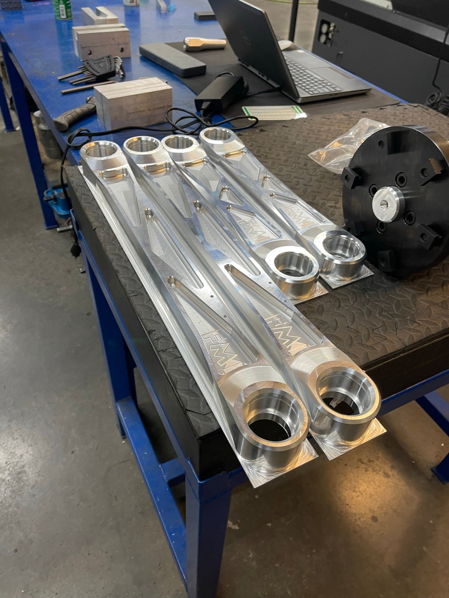 Bronco Raptor rear suspension kit featuring billet aluminum rear arms displayed on a workbench in a workshop.
