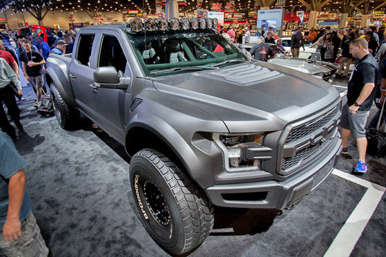 2017 Up Raptor Long Travel Front Suspension Kit displayed on a modified truck at an automotive expo, showcasing offroad capabilities.