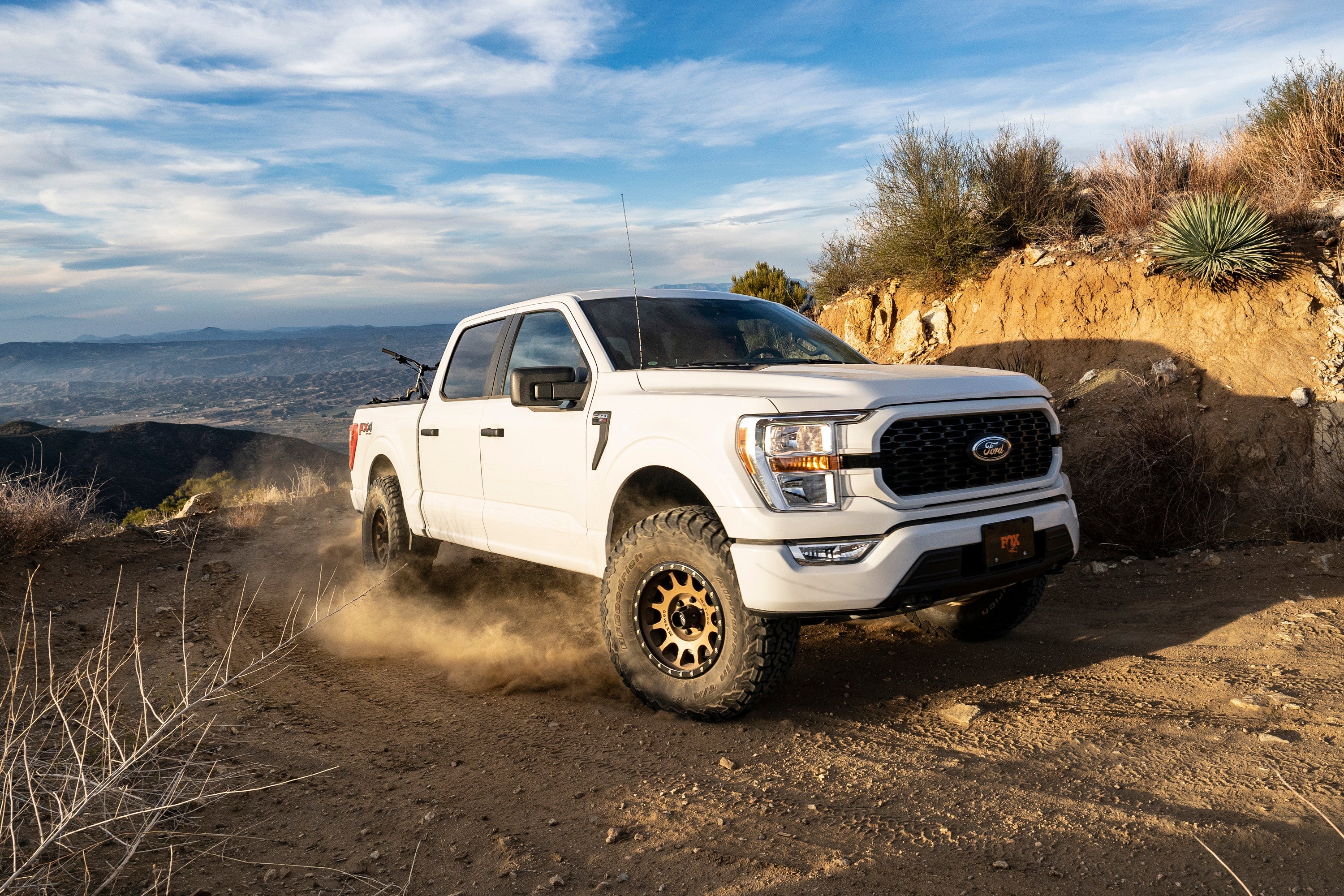 Ford F150 4WD equipped with a 2-inch leveling kit and 2.5 Performance Elite Series, driving off-road on rugged terrain.