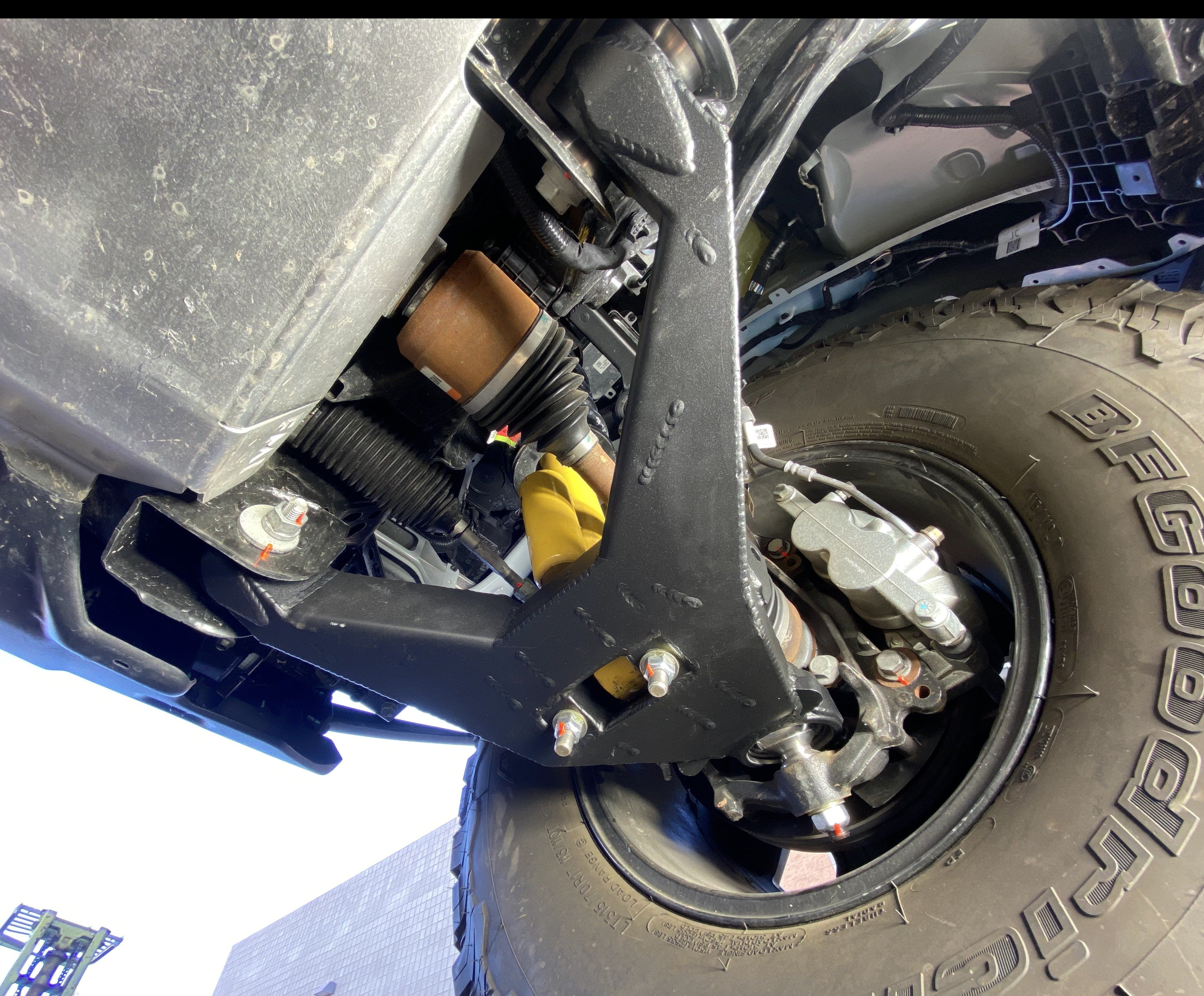 2021 and up Bronco fabricated lower arm kit with bypass shock mount installed on a vehicle, showcasing stock length components.