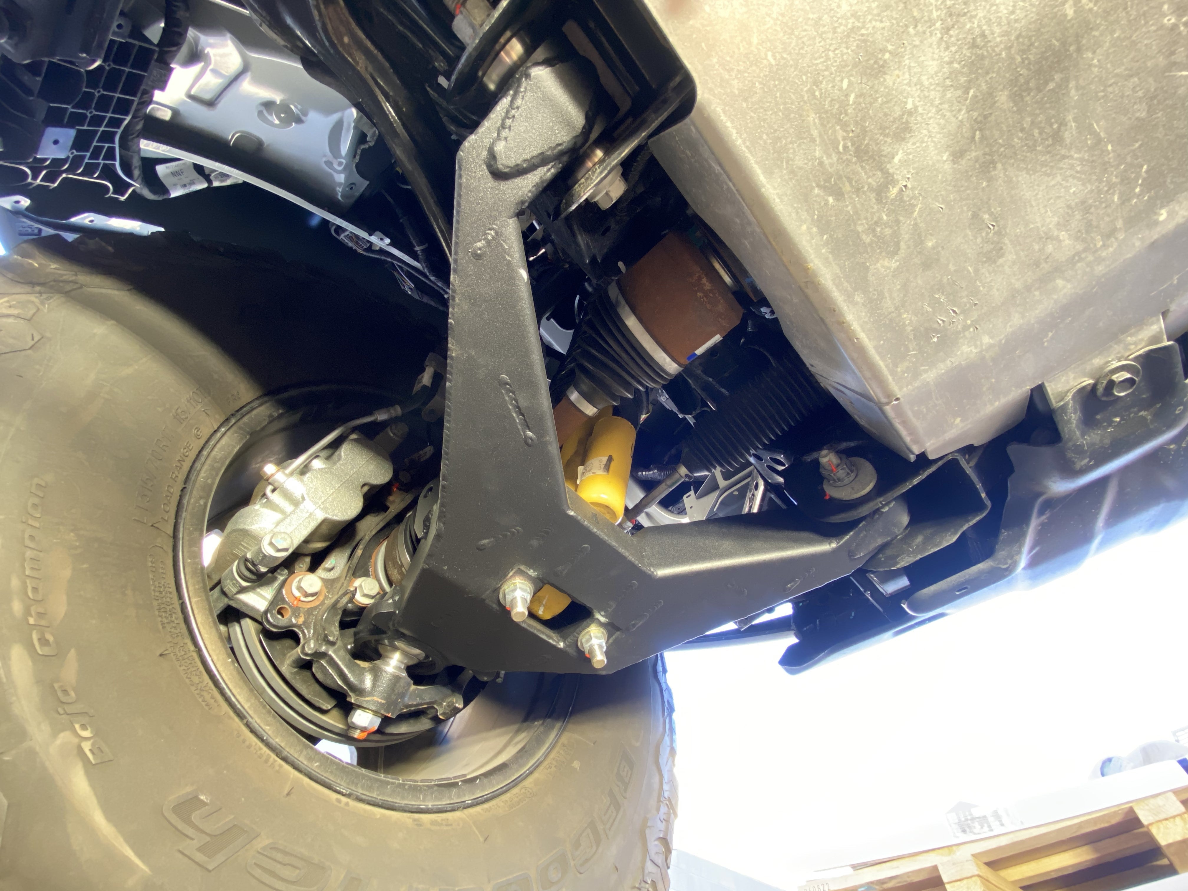 2021 and up Bronco fabricated lower arm kit with bypass shock mount, showcasing stock length installation under vehicle.