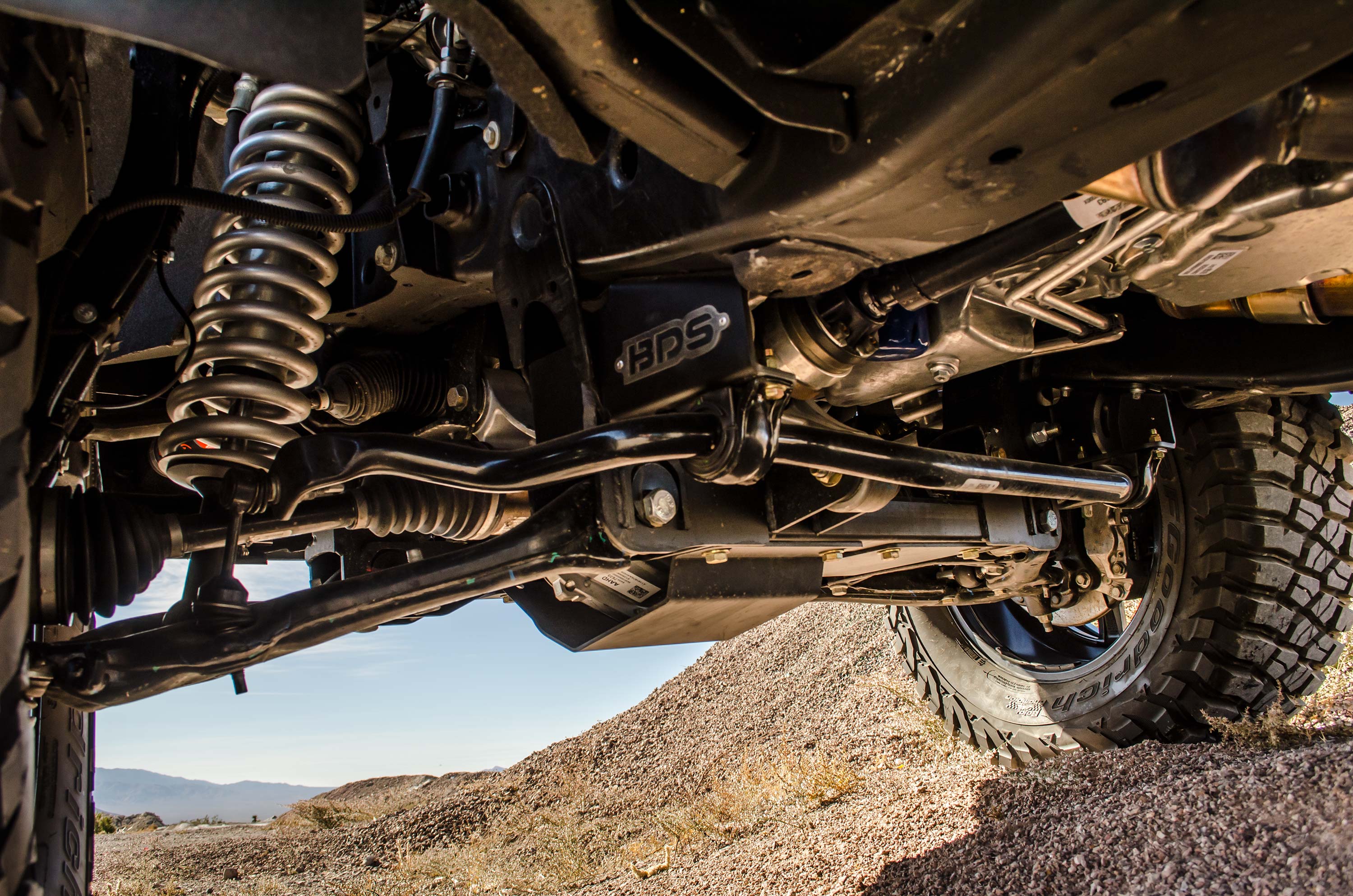 Close-up view of a 6-inch lift kit installed on a Chevy Silverado or GMC Sierra 1500, showcasing suspension components and undercarriage details.