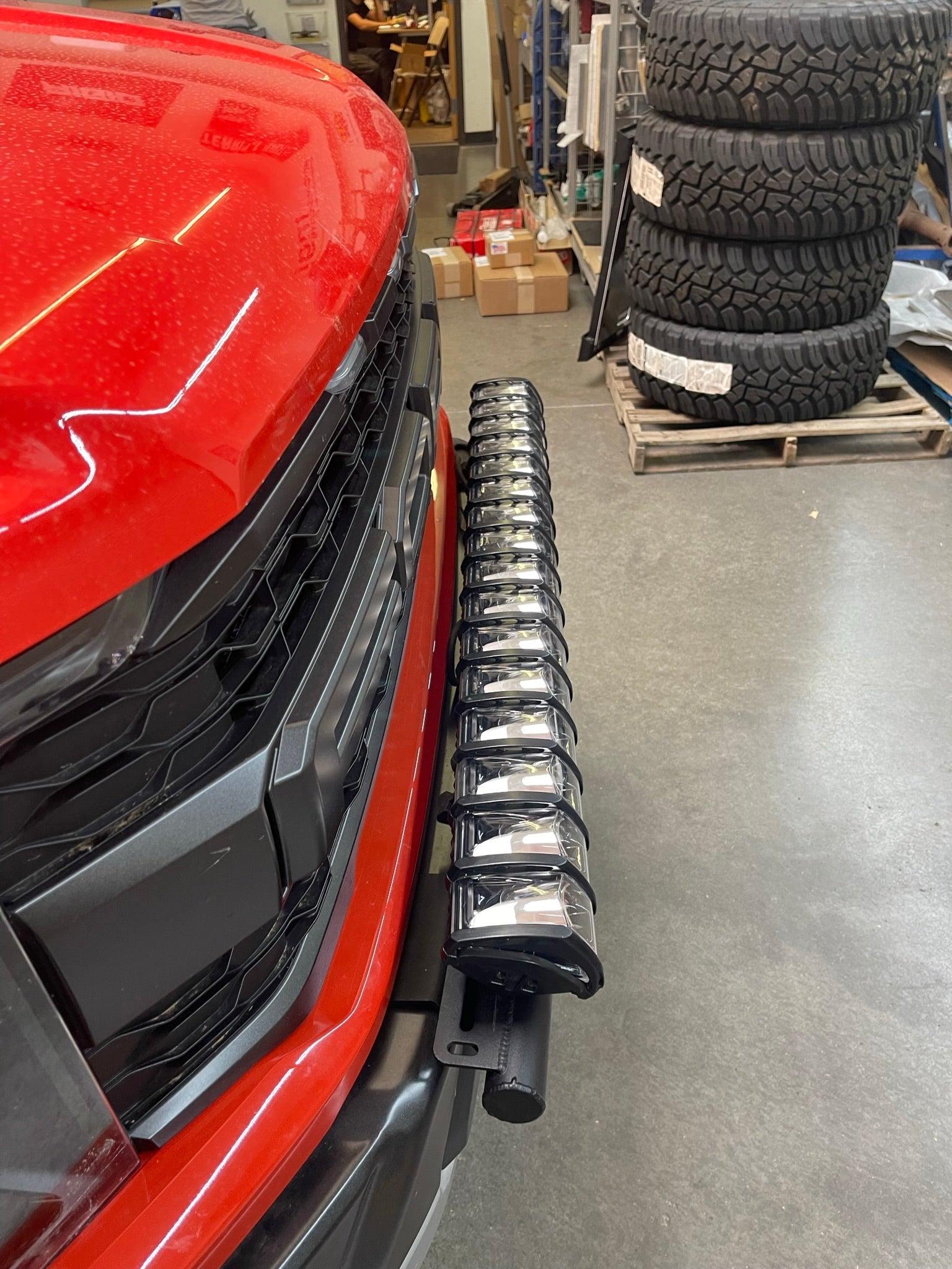 2024 Raptor front light mount kit on a red truck, showcasing a modular bumper with multiple light options.