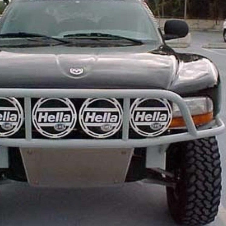Black 1998-2003 Dodge Durango with aftermarket fenders and Hella lights on a front grille, showcasing offroad style.