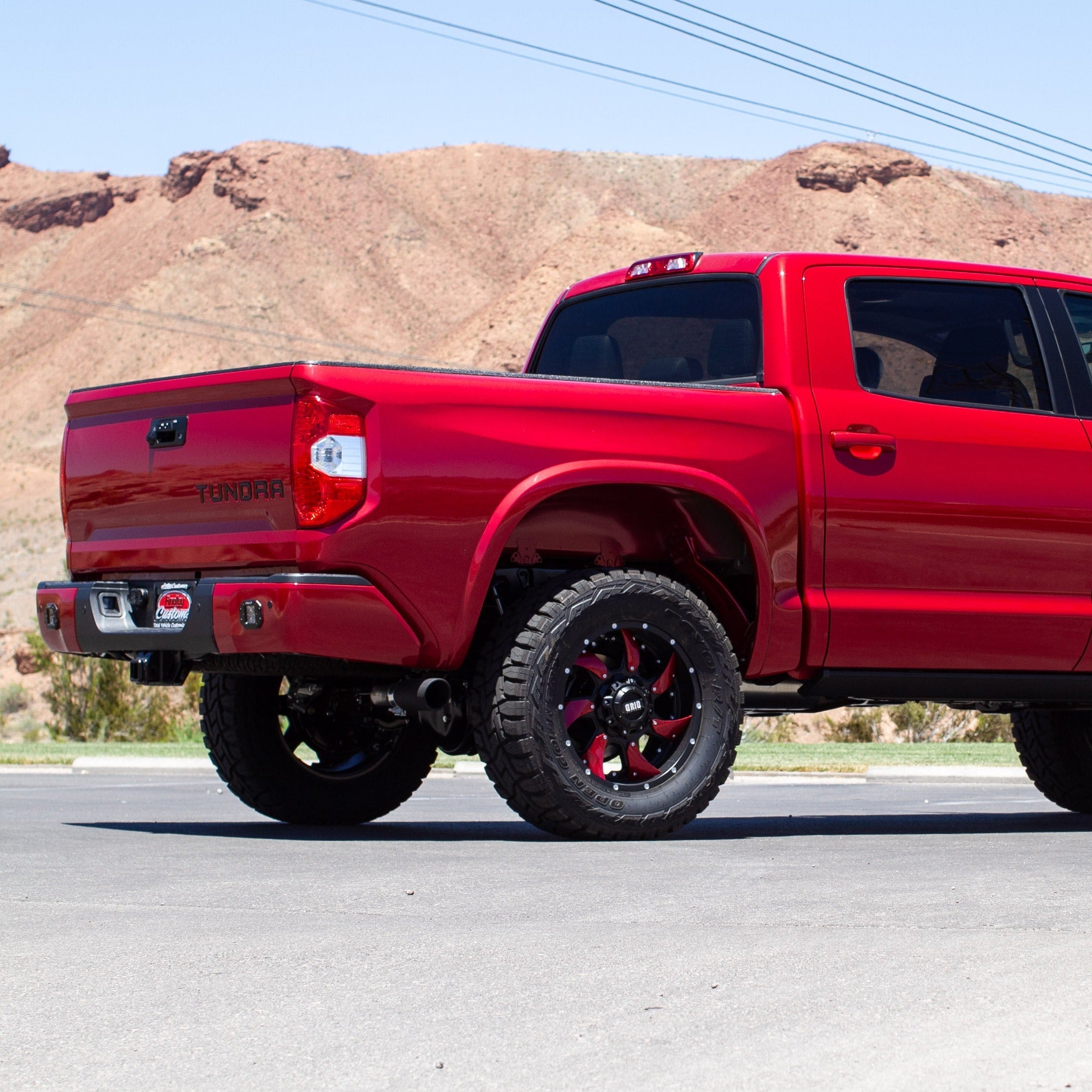 2014-2021 Toyota Tundra with custom bedsides, showcasing a bold red color and off-road tires against a desert backdrop.