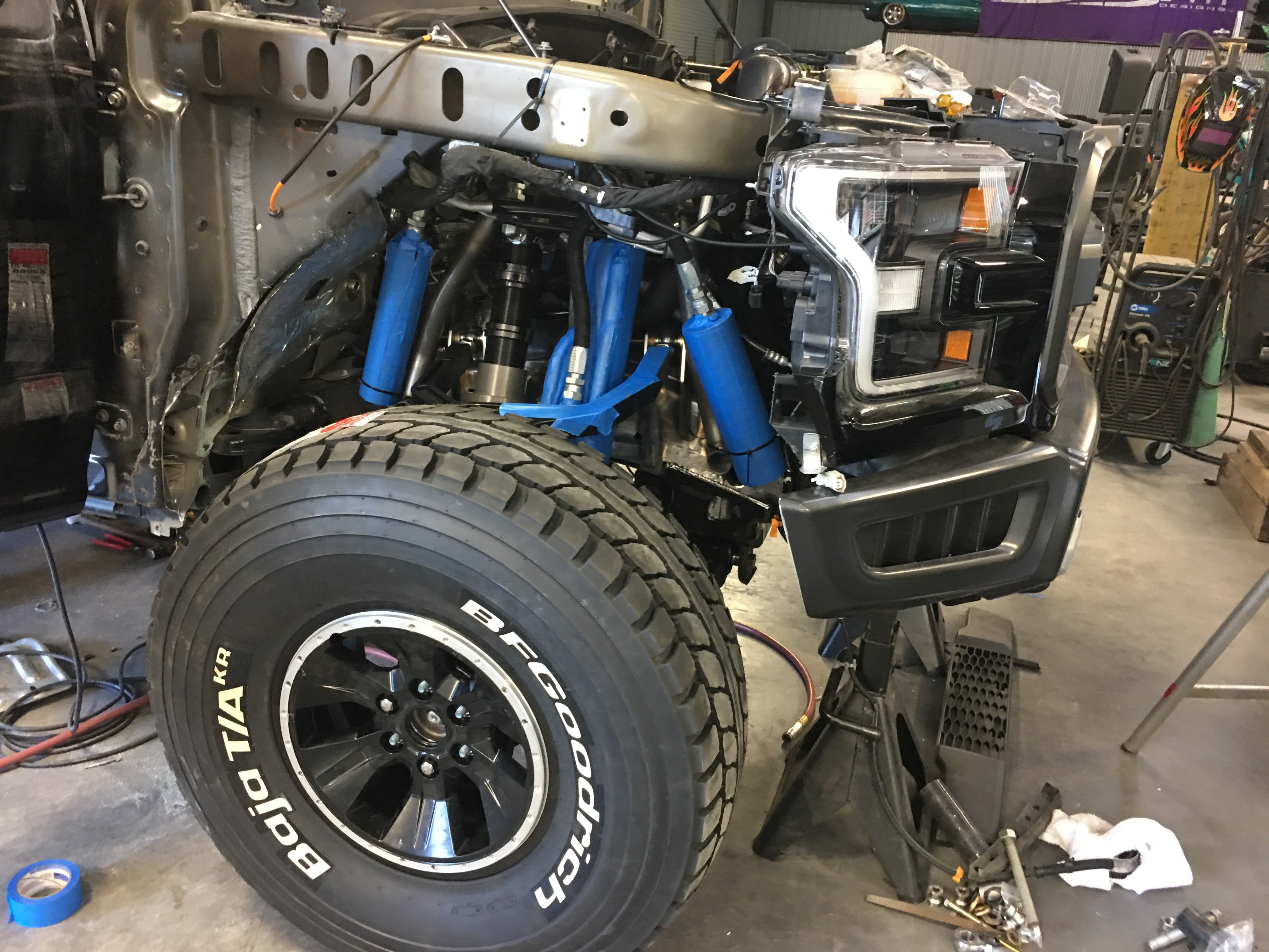 2017 Up Raptor Long Travel Front Suspension Kit installed on a truck, showcasing blue shock absorbers and rugged tires.
