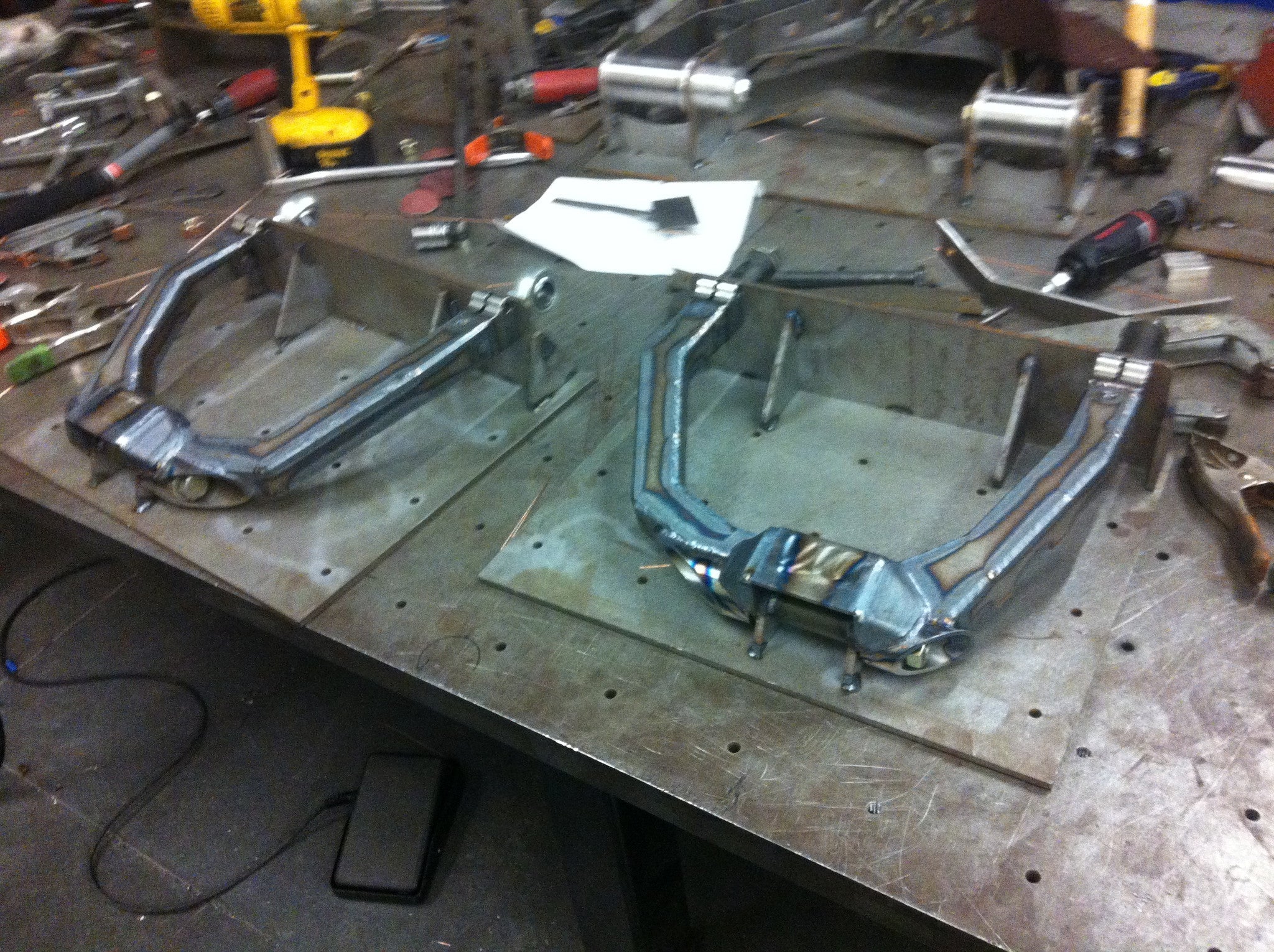 Long travel front suspension kit for 2010-2014 Raptor, showcasing precision-engineered components on a workbench.
