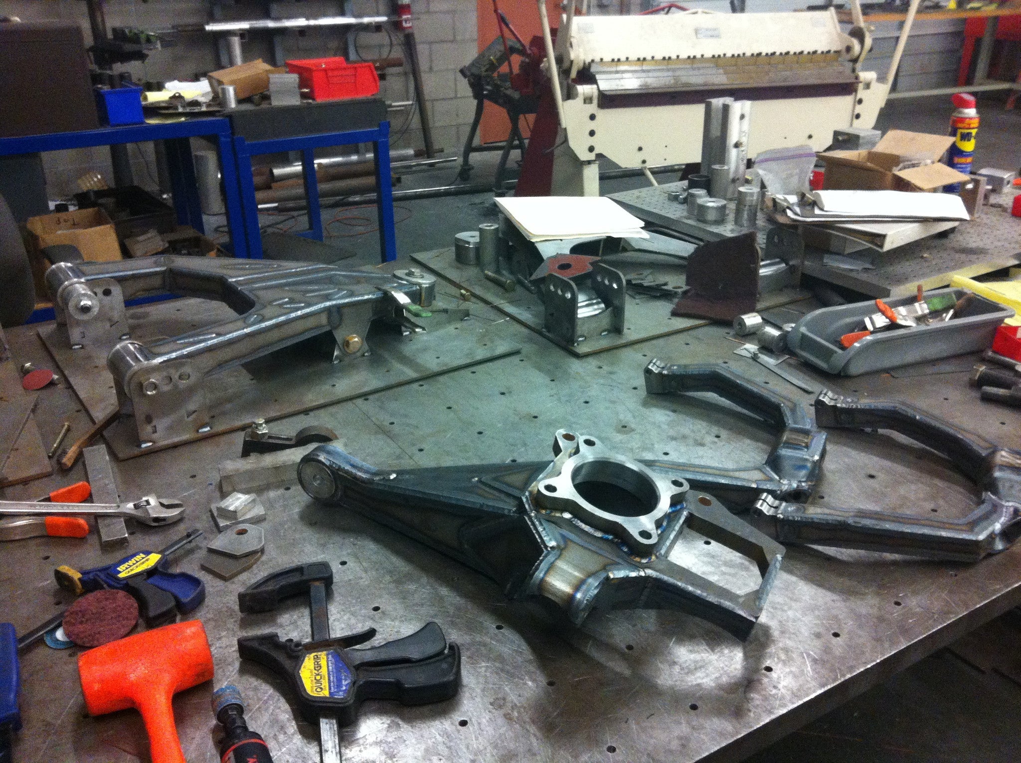 Long travel front suspension kit for 2010-2014 Raptor displayed on a workshop table with various tools and components.