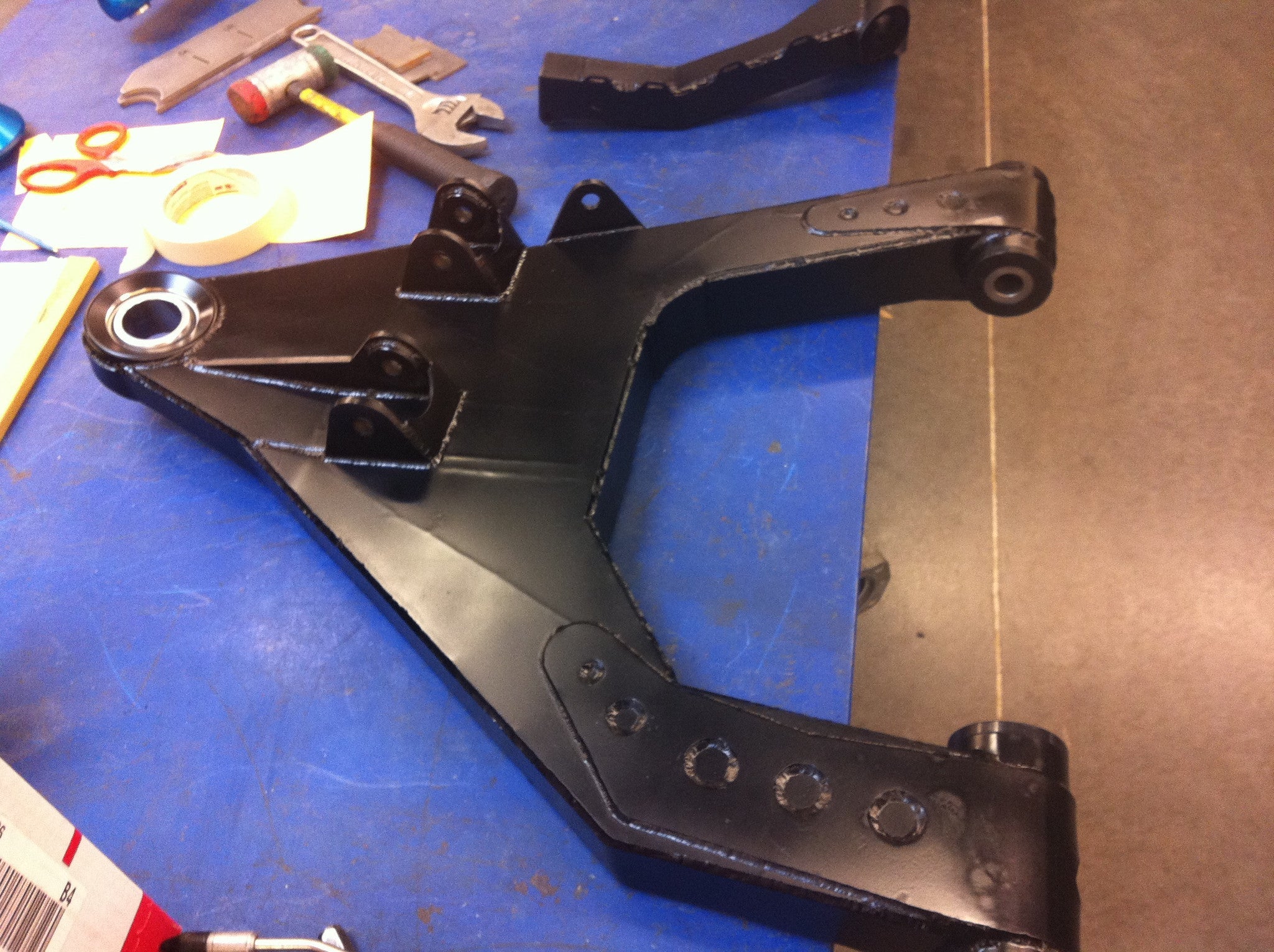 2010-2014 Raptor long travel front suspension kit component on a workbench, showcasing its robust design and construction.