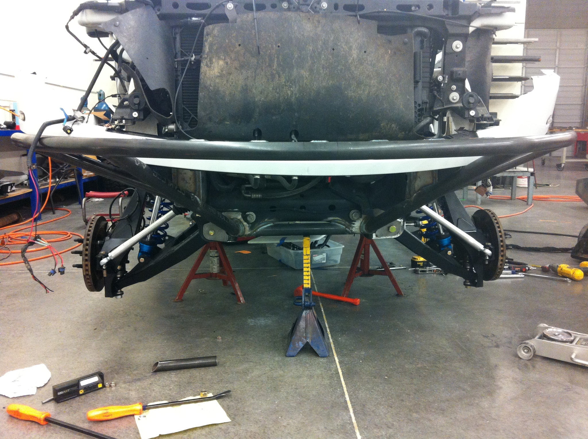 Long travel front suspension kit for 2010-2014 Raptor, showcasing components and installation setup in a workshop.