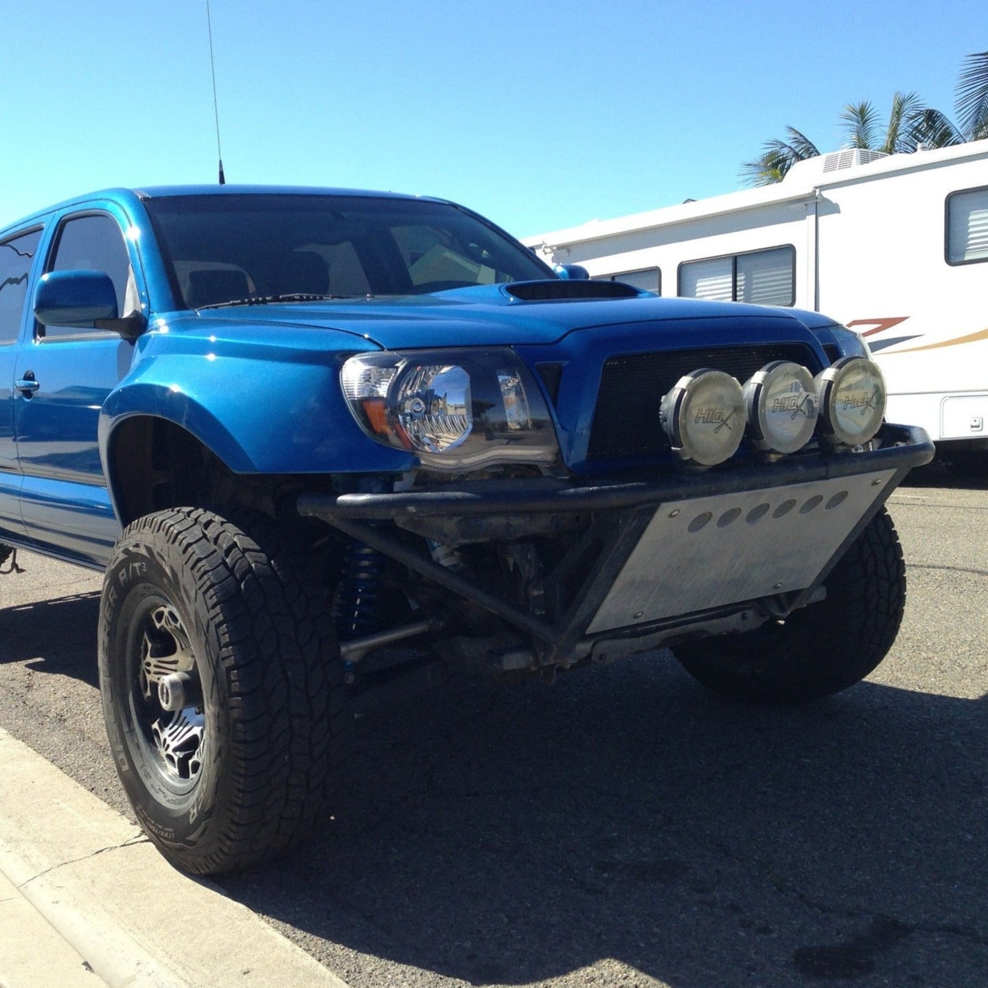 Blue 2005-2015 Toyota Tacoma with offroad fenders and upgraded lighting, showcasing rugged design and enhanced performance.