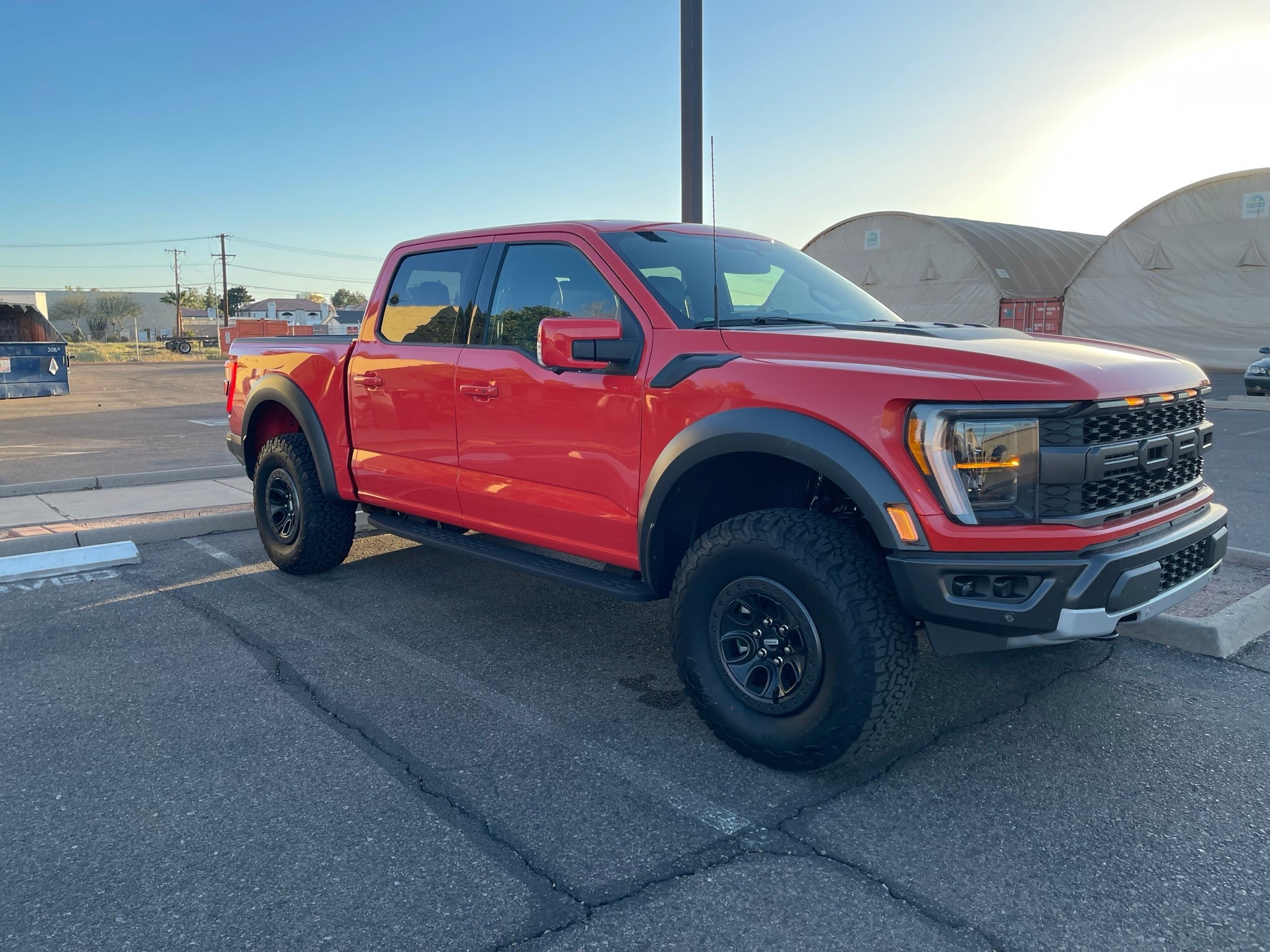 2021 and up Raptor front leveling kit showcasing a lifted red truck with rugged tires in an outdoor setting.