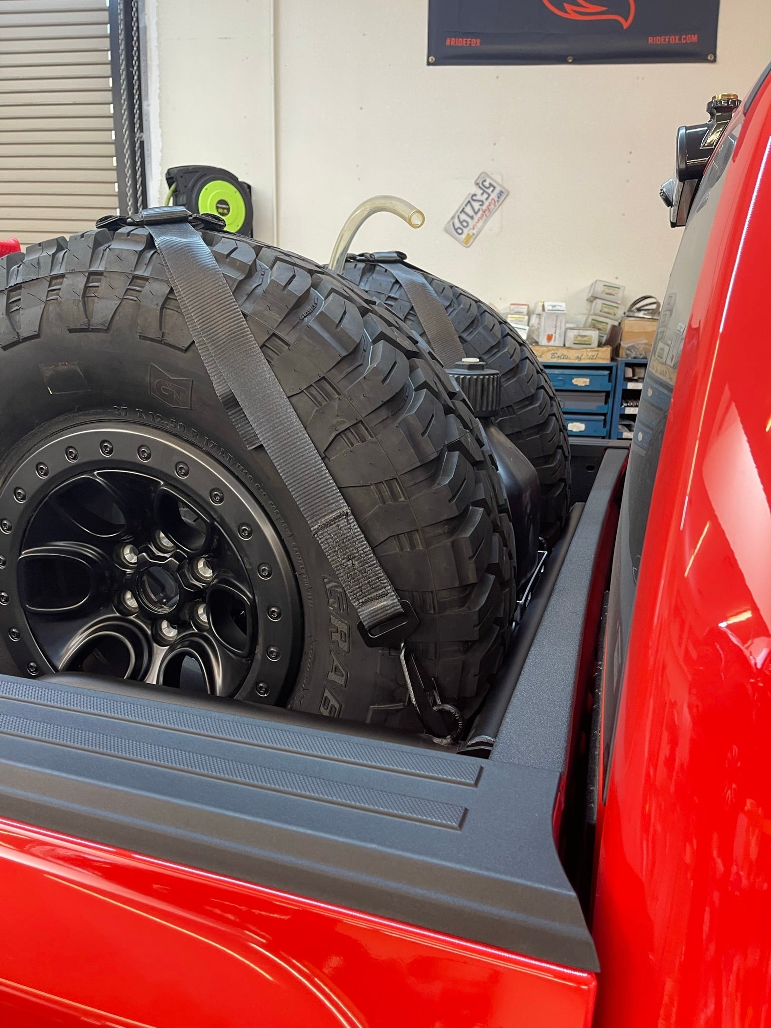 Ford Raptor modular bed organizer with slide-out cargo tray, featuring securely strapped tires in a truck bed.