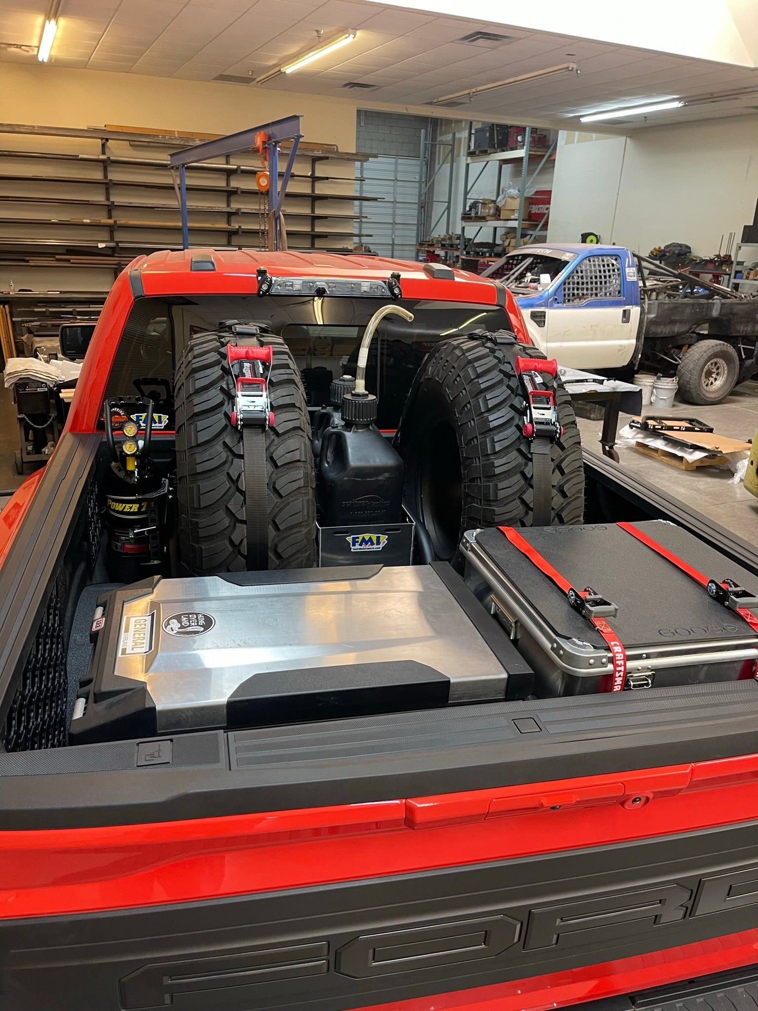 Ford Raptor modular bed organizer with slide-out cargo tray, showcasing tires, tools, and gear in a truck bed.