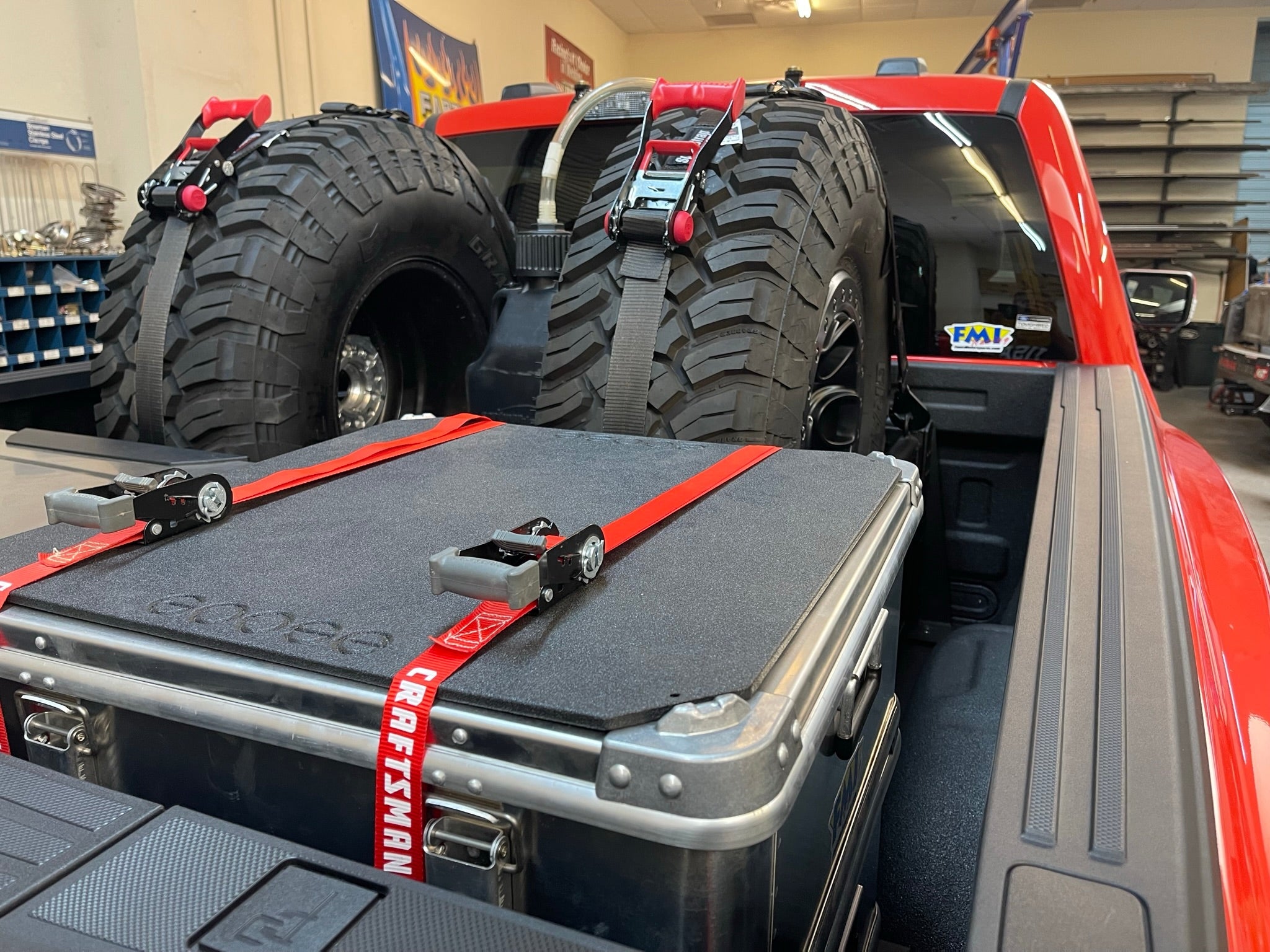 Ford Raptor modular bed organizer with slide-out cargo tray, featuring secured tires and a storage box in a truck bed.