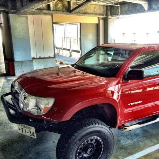 2005-2015 Toyota Tacoma fenders displayed on a lifted red Tacoma in a parking garage, showcasing offroad style and durability.