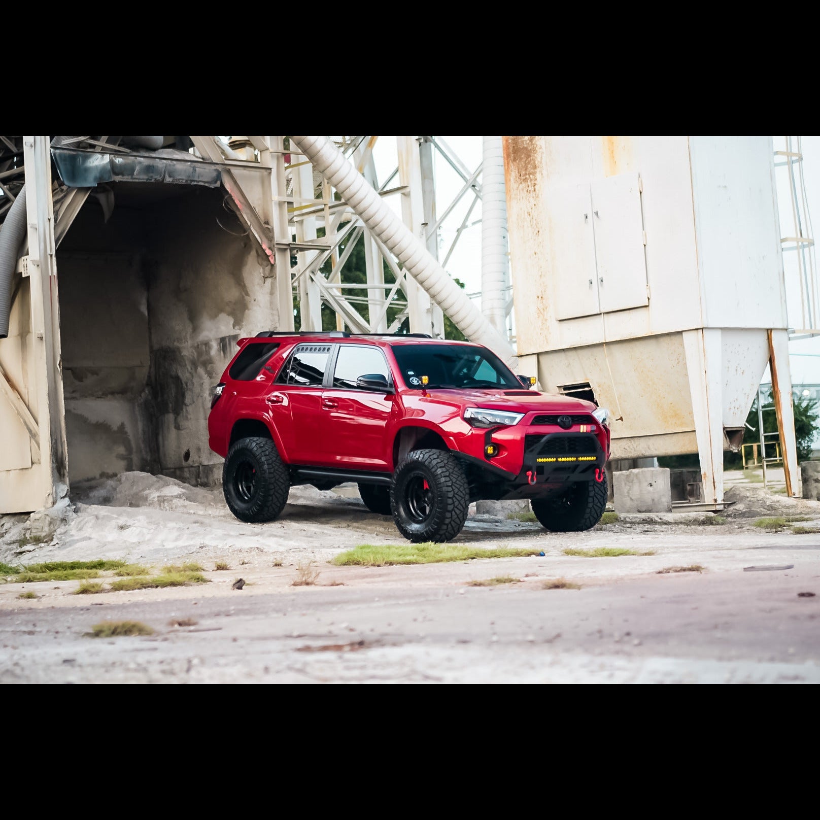 4Runner Lo-Pro winch bumper for 5th Gen models, showcasing a red SUV with offroad tires in an industrial setting.