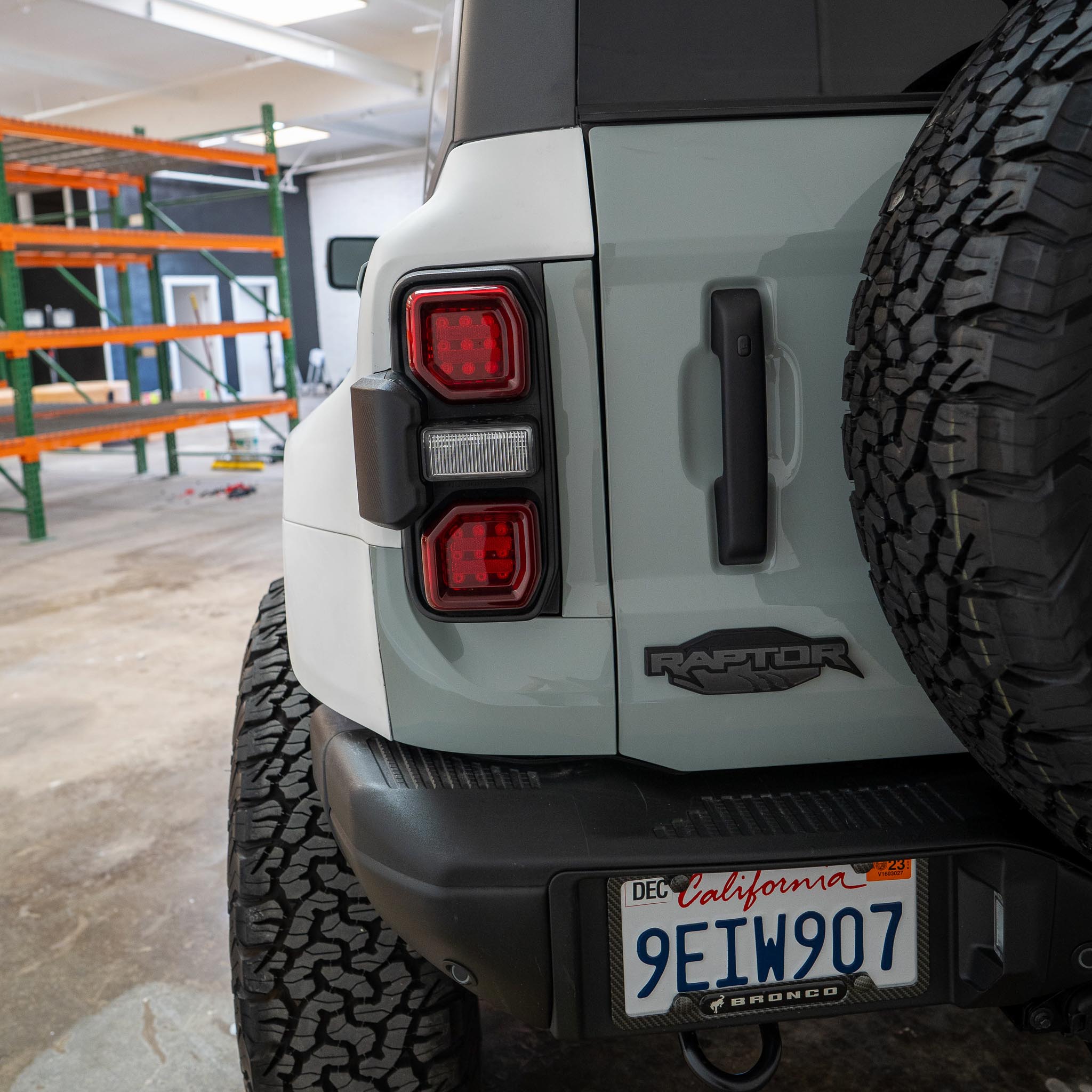 2022-2025 Ford Bronco Raptor rear quarter kit showcasing taillights and rugged tire design in a workshop setting.