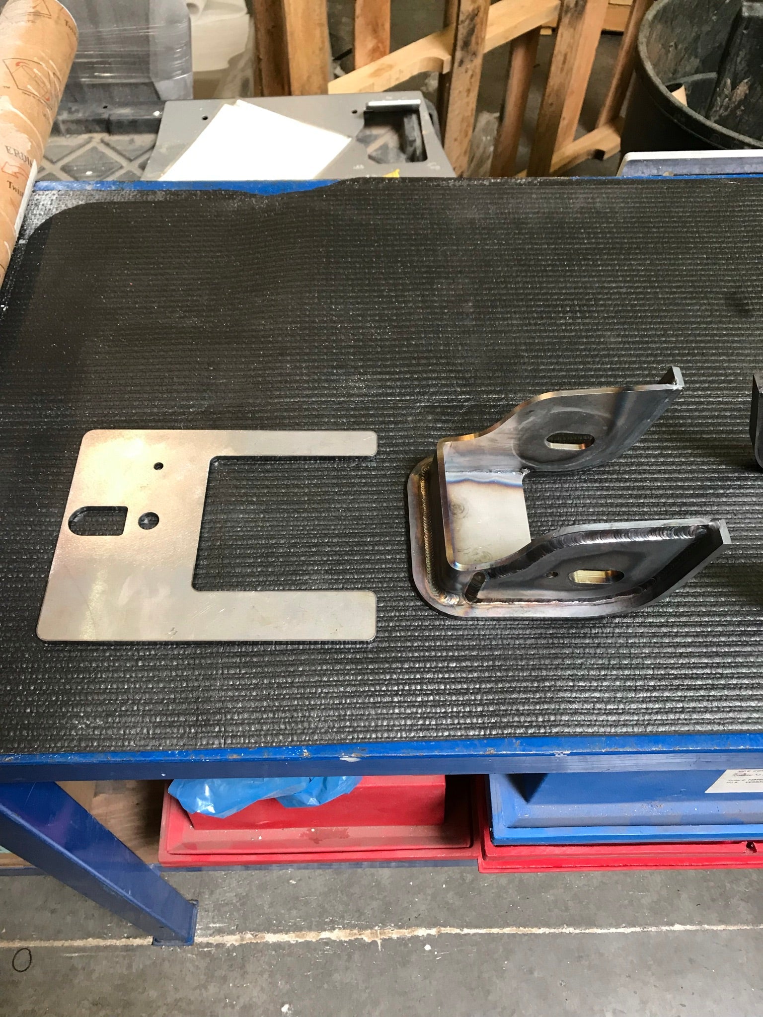 Lower arm pocket replacement kit for 2017-2024 Raptor by Foutz Motorsports, featuring metal components on a workbench.