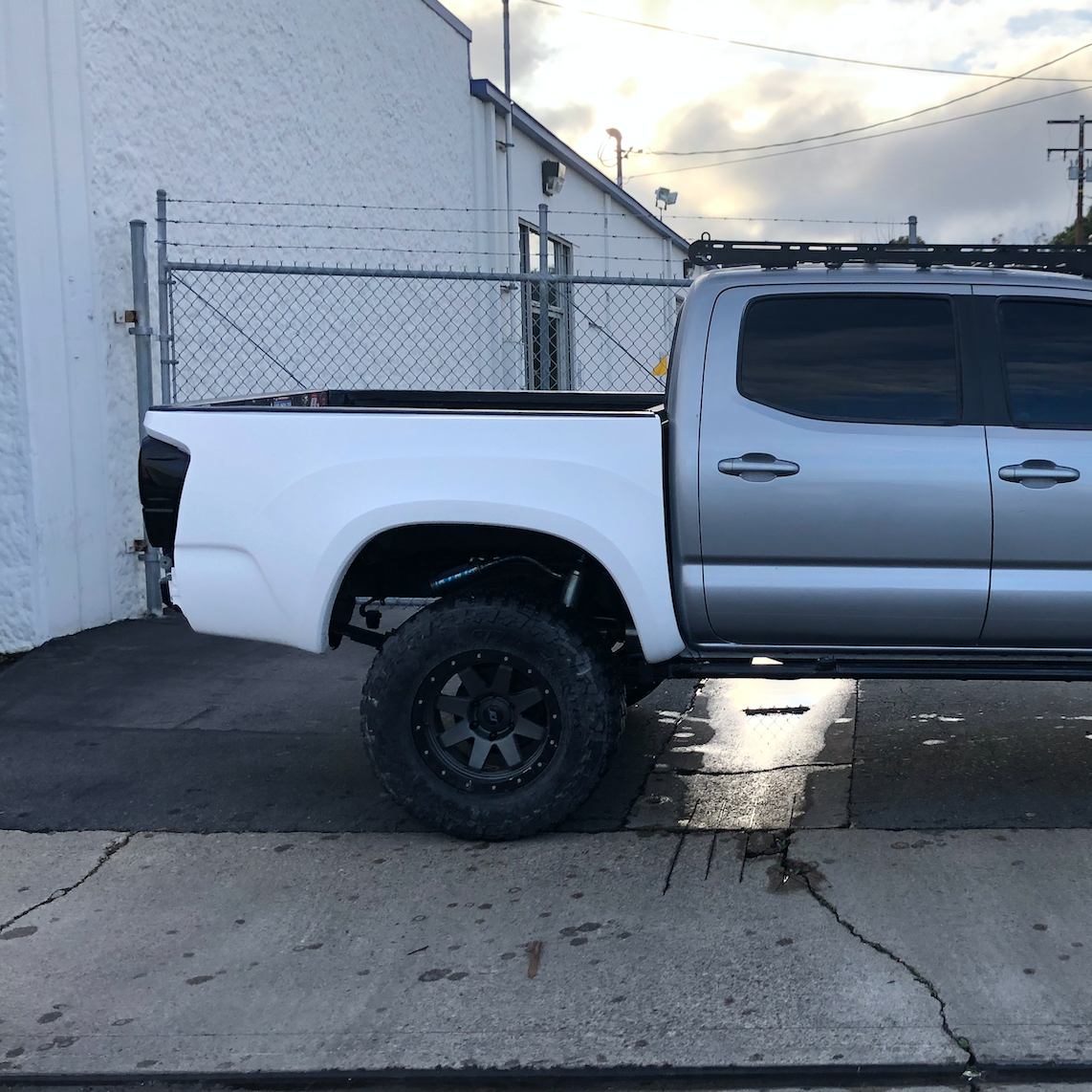 2016-2023 Toyota Tacoma with custom white bedsides, showcasing an elevated offroad stance and rugged tires.