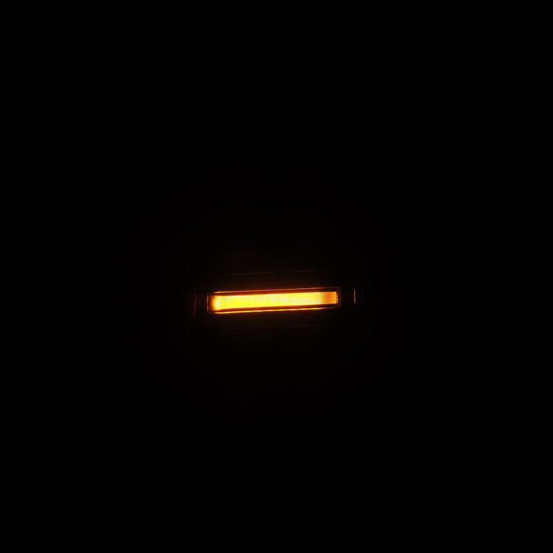 AlphaRex NOVA LED tail light for 05-15 Toyota Tacoma in black, showcasing a bright amber light.