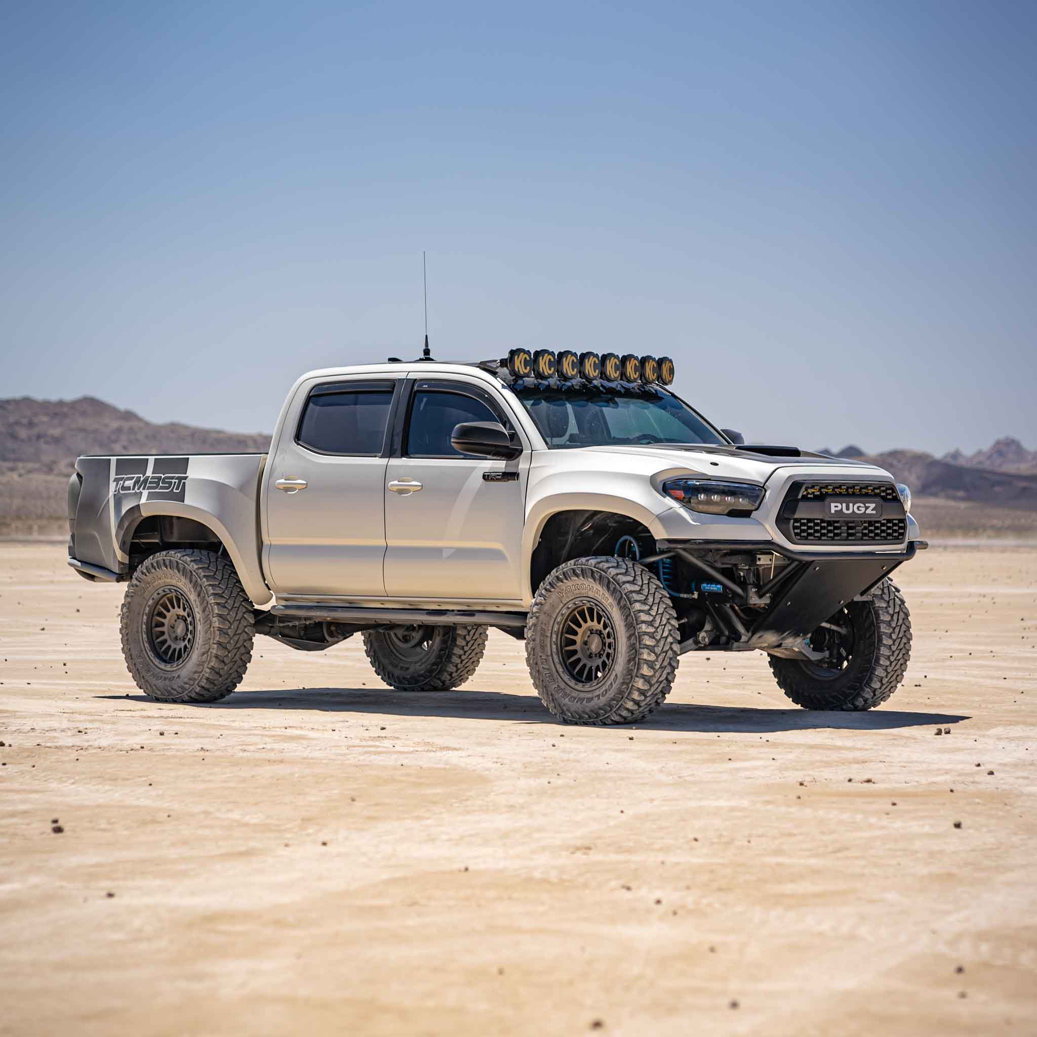 2016-2023 Toyota Tacoma with custom bedsides, offroad tires, and roof lights in a desert landscape.