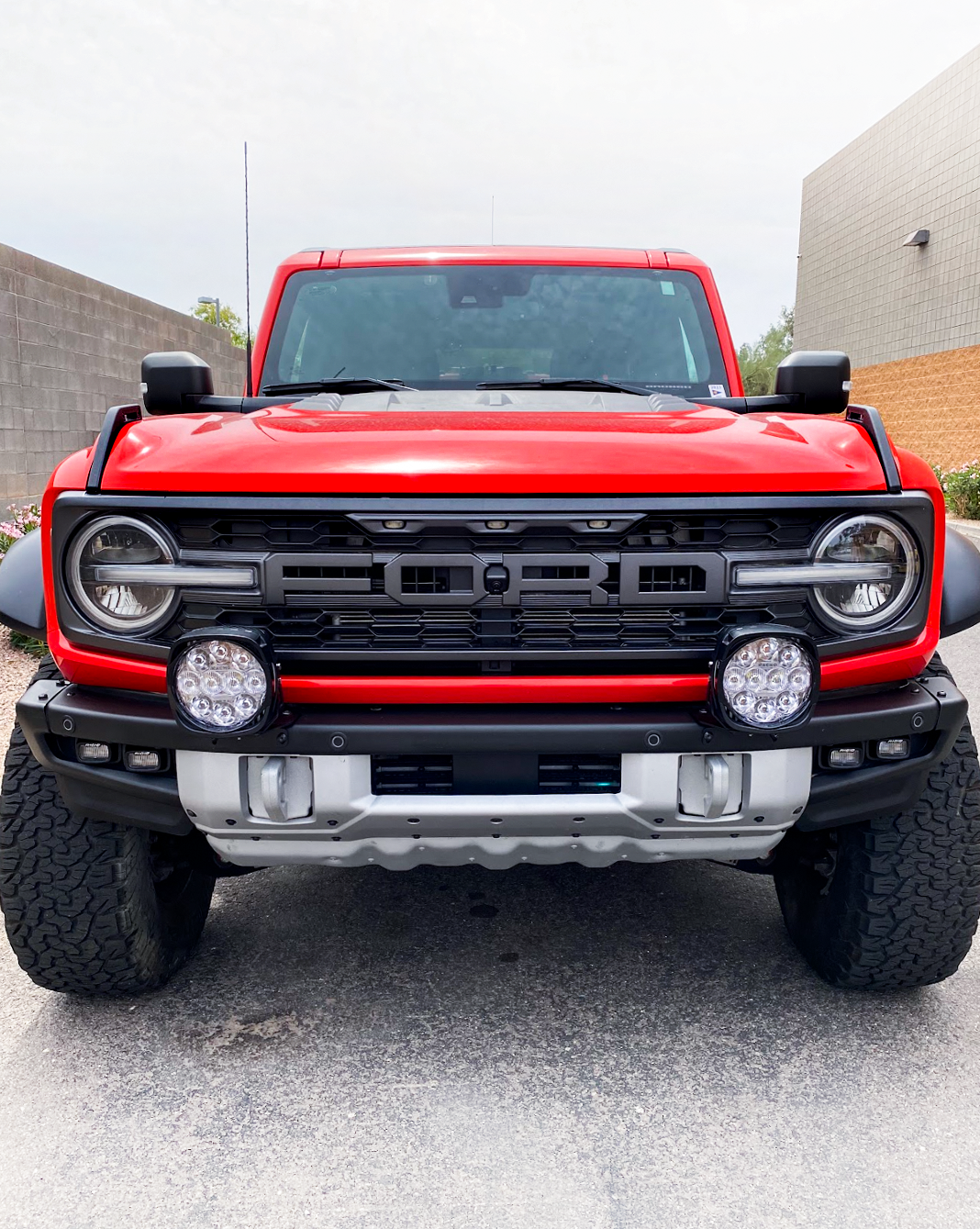 Front view of a red 2022-2024 Bronco Raptor with light mount brackets installed on the stock modular bumper.