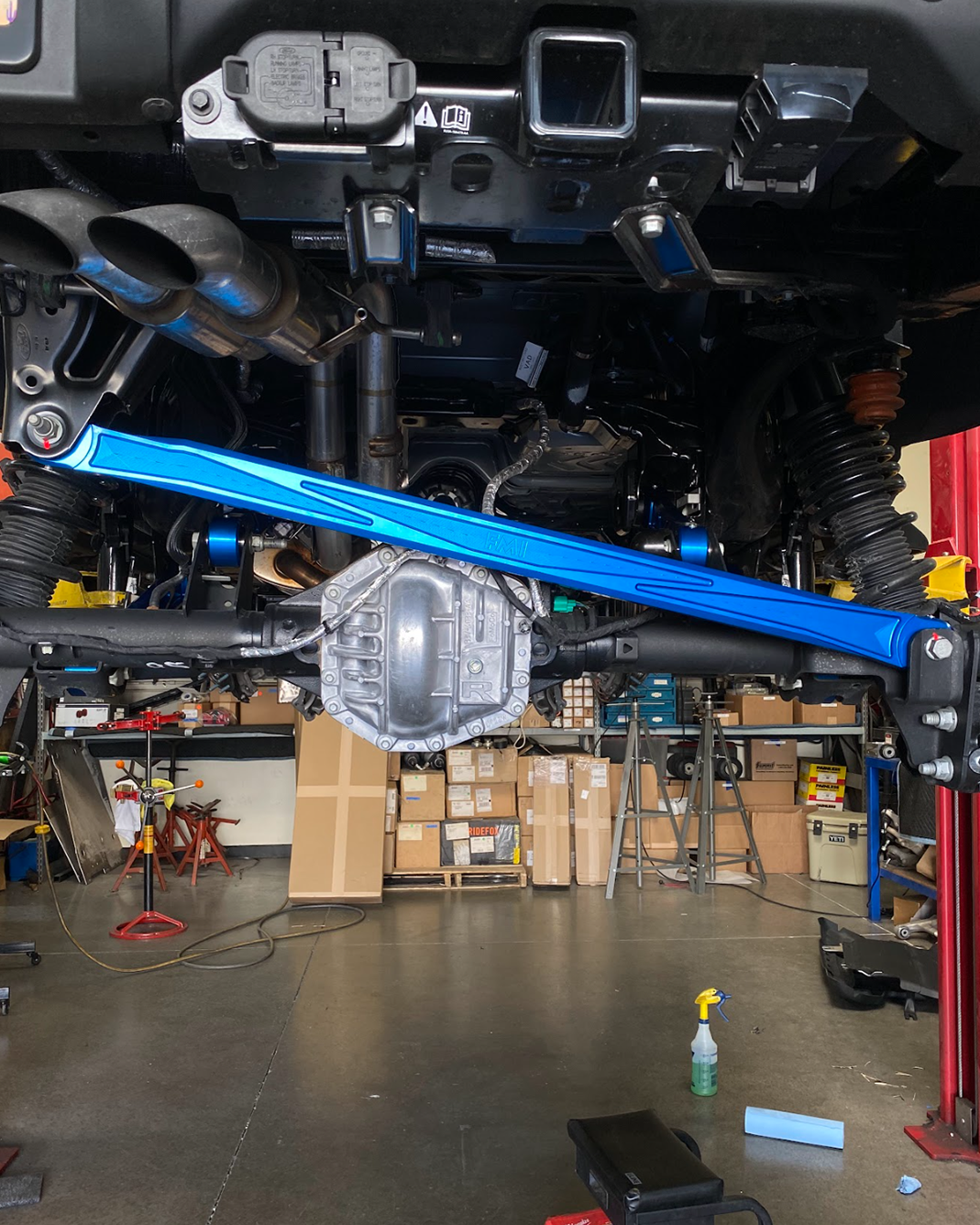2022+ Bronco Raptor billet panhard bar with ultra-flex joint installed under a vehicle in a workshop setting.