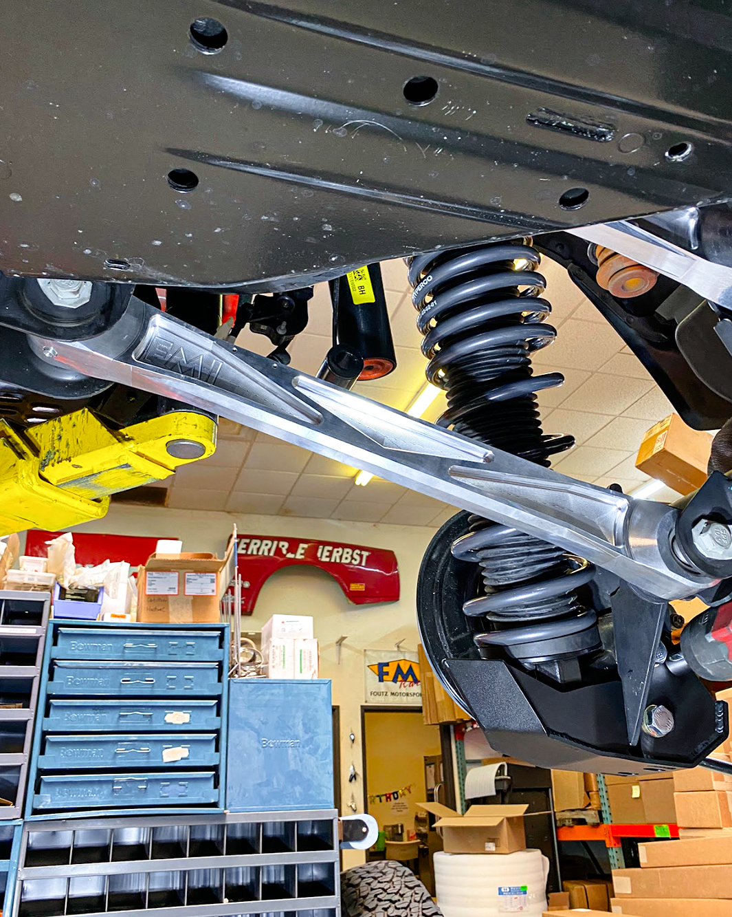 Billet aluminum rear lower suspension arms with ultra-flex joints installed on a 2022 Bronco Raptor in a workshop setting.