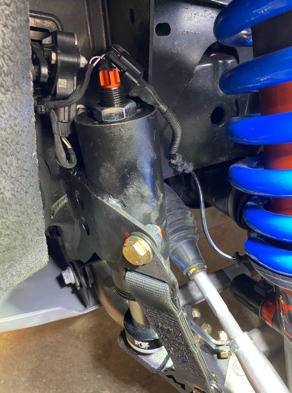 Front limit strap and bump stop for 2022+ Bronco Raptor, installed on stock lower arm, showcasing suspension components.