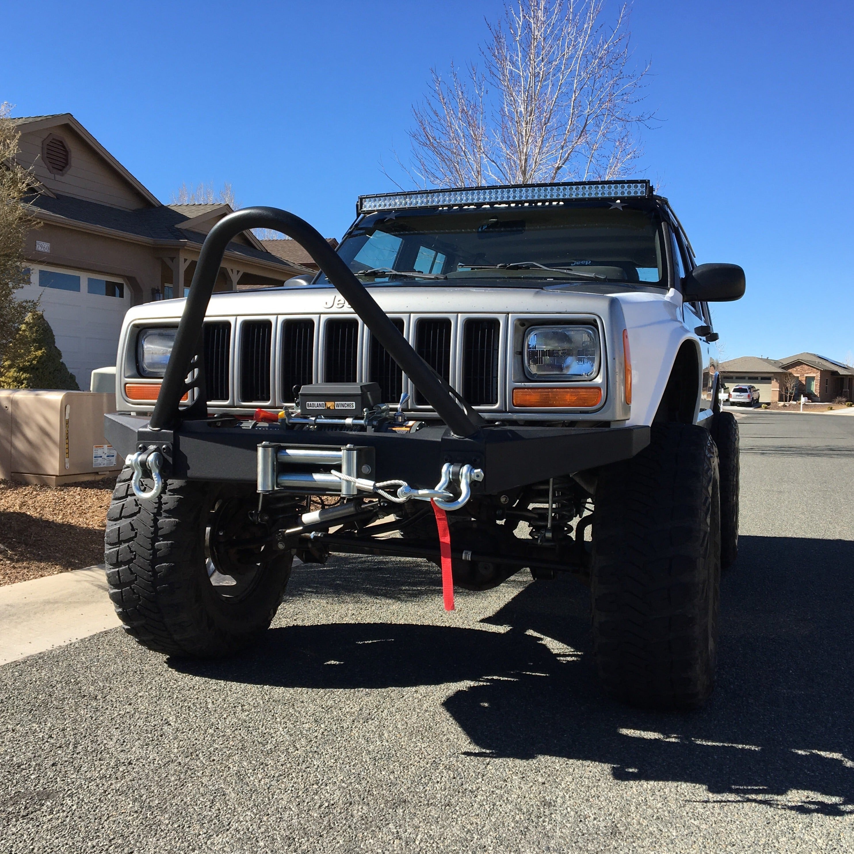 Front view of a modified 1986-1992 Jeep Comanche with rugged fenders and offroad accessories, parked on a residential street.