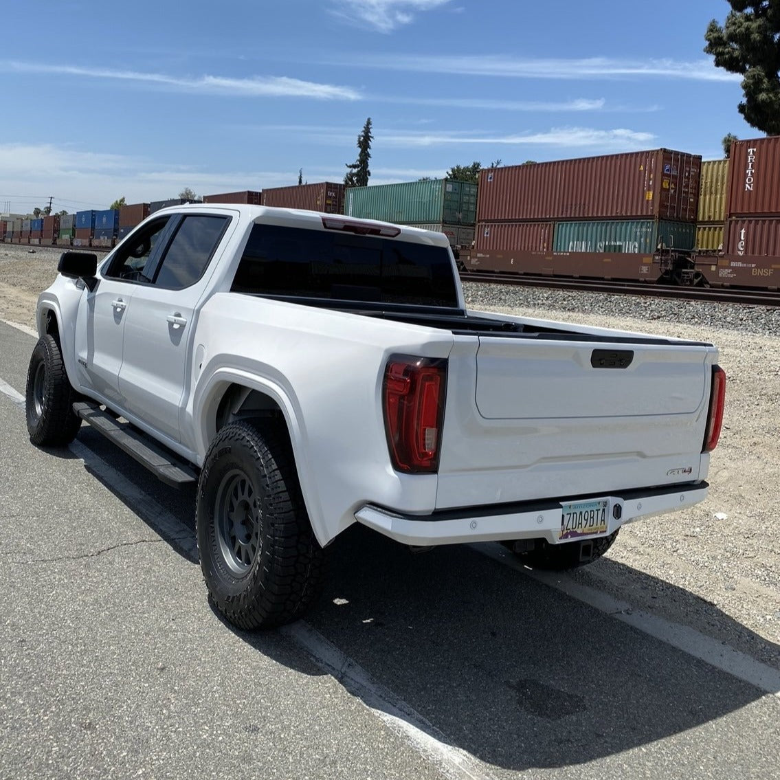 2019-2025 GMC Sierra with custom bedsides, showcasing a sleek design and off-road tires in an industrial setting.