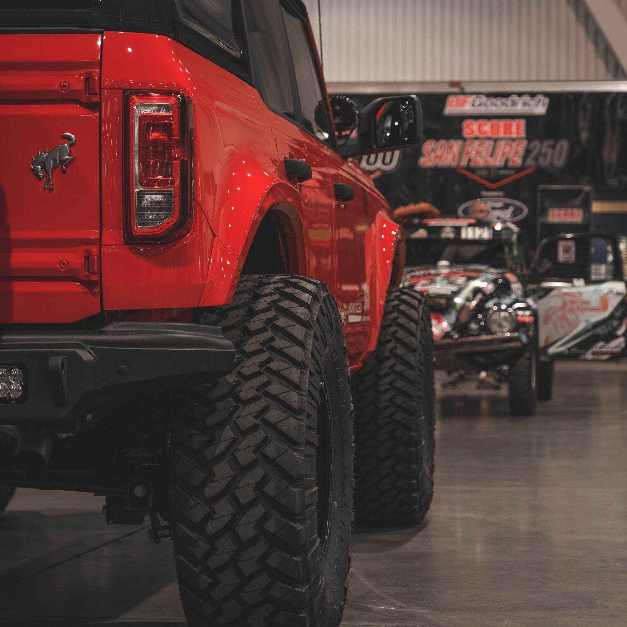 2021-2025 Ford Bronco 4-Door Rear Quarter Kit showcasing a red Bronco with rugged tires in an automotive exhibition setting.